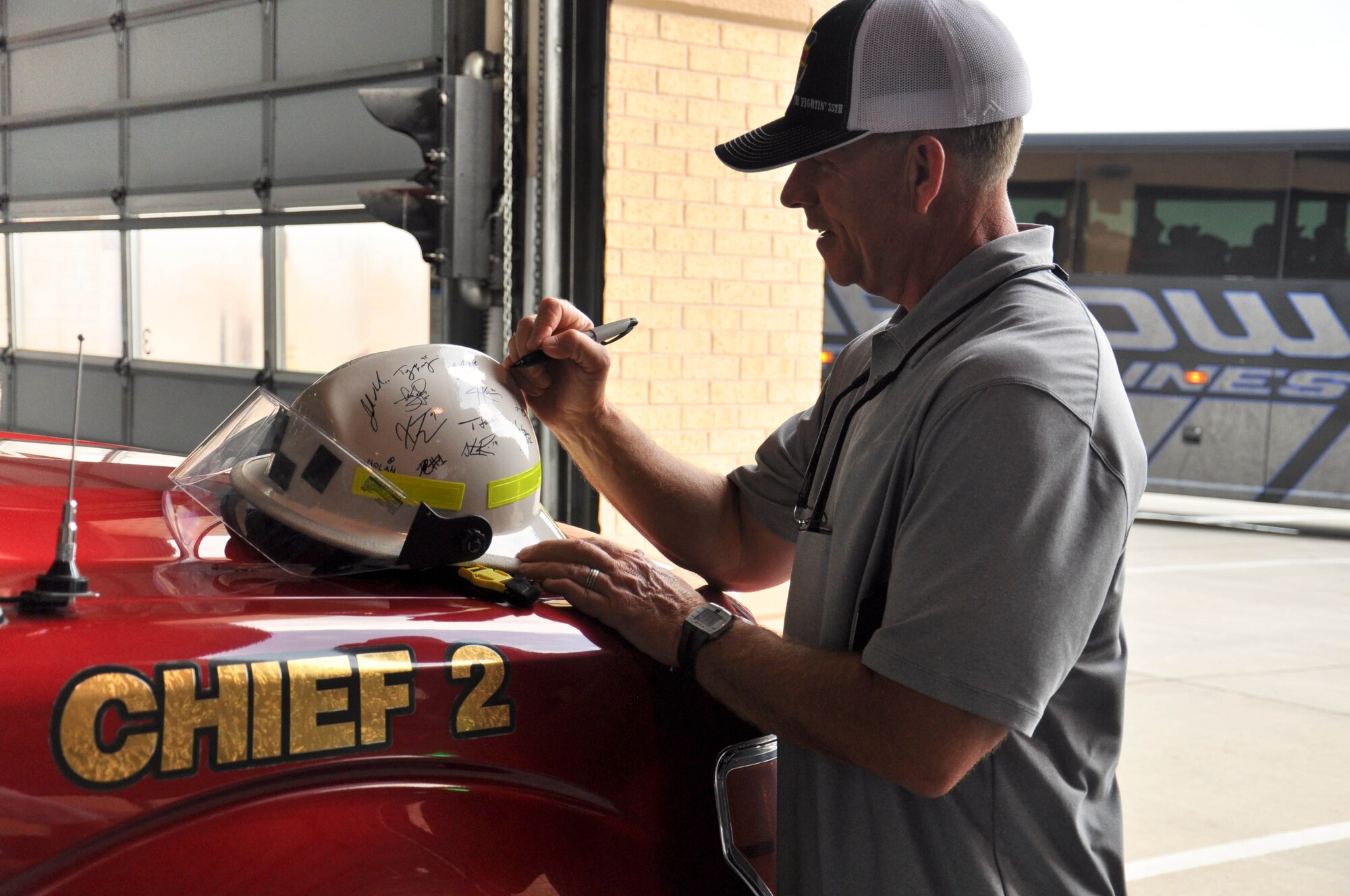 Tim Corbin, Vanderbilt University head coach, signs a firefighter helmet at the Offutt Air Force Base fire house June 19. Corbin and his team visited base as part of a partnership between the 55th Wing and the College World Series. (U.S. Air Force photo by 2nd Lt. Carly Costello)