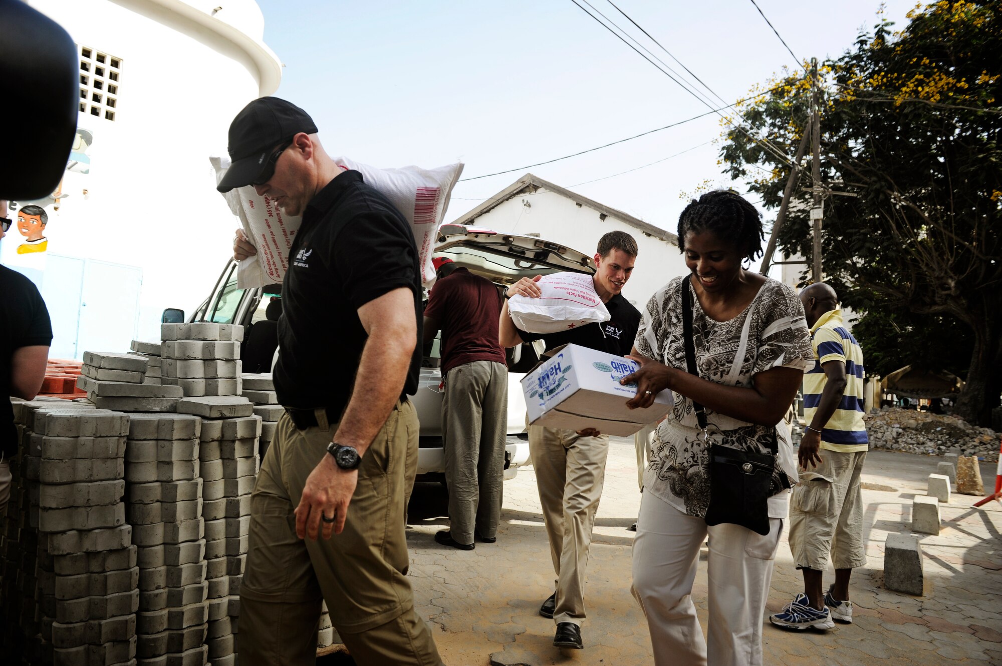 Members of the U.S. Air Forces in Europe and Air Forces Africa rock band, "Afterburner", carry donated food into an orphanage prior to a concert there in Dakar, Senegal June 18, 2014. USAFE-AFAFRICA Airmen are in Senegal for African Partnership Flight, a program designed to improve communication and interoperabilty between regional partners in Africa. The band will be playing multiple venues in the area to inspire children and musicians through the universal language of music. (U.S. Air Force photo/ Staff Sgt. Ryan Crane)