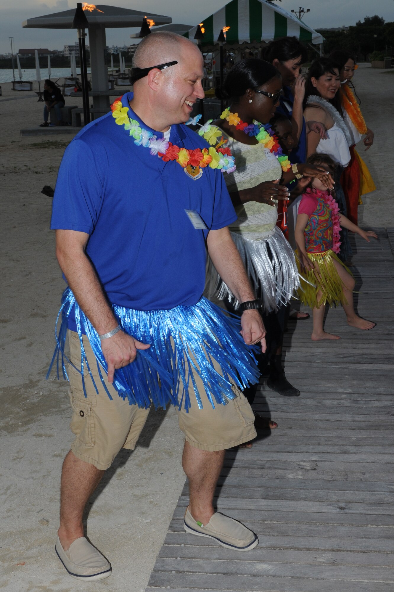 U.S. Air Force Chief Master Sgt. Jeffrey Martin, 18th Mission Support Group superintendent, and members of the audience take part in hula dancing during the Deployed Spouses Luau on Torii Beach, Japan, June 21, 2014. The luau was open to all branches of the military to show support for the families of deployed service members. and was hosted by Army Community Service on Torii Station and the Airman and Family Readiness Center on Kadena Air Base. (U.S. Air Force photo by Airman 1st Class Stephen G. Eigel)