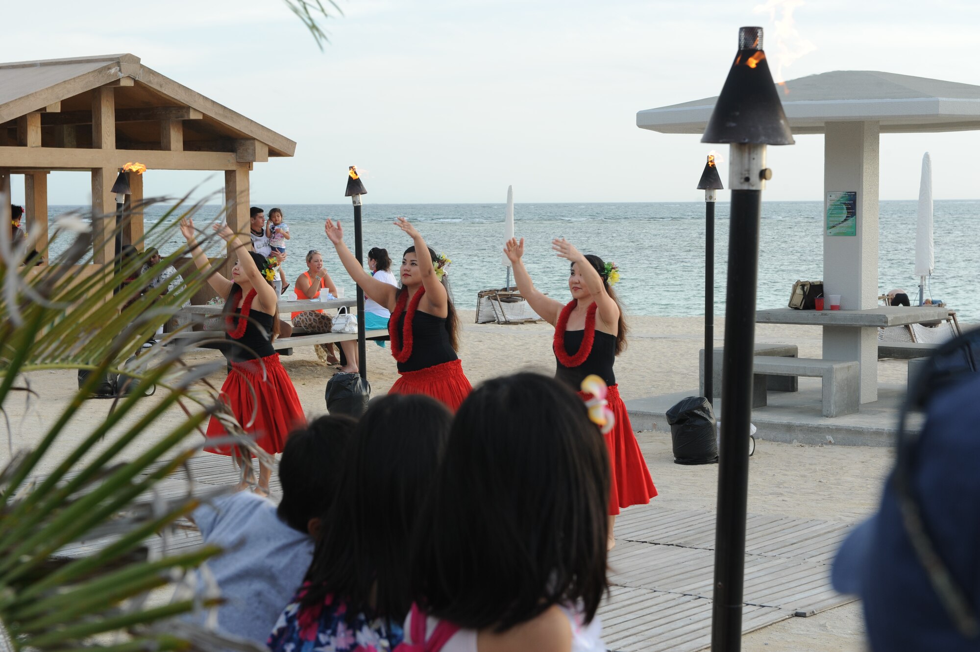 Attendees look on as Okinawa's Hui Nohona Aloha dance group performs an array of hula dances during the Deployed Spouses Luau on Torii Beach, Japan, June 21, 2014. The luau was arranged by Airman and Family Readiness Center as well as Army Community Services to show support for the spouses and families of deployed service members.(U.S. Air Force photo by Airman 1st Class Stephen G. Eigel)
