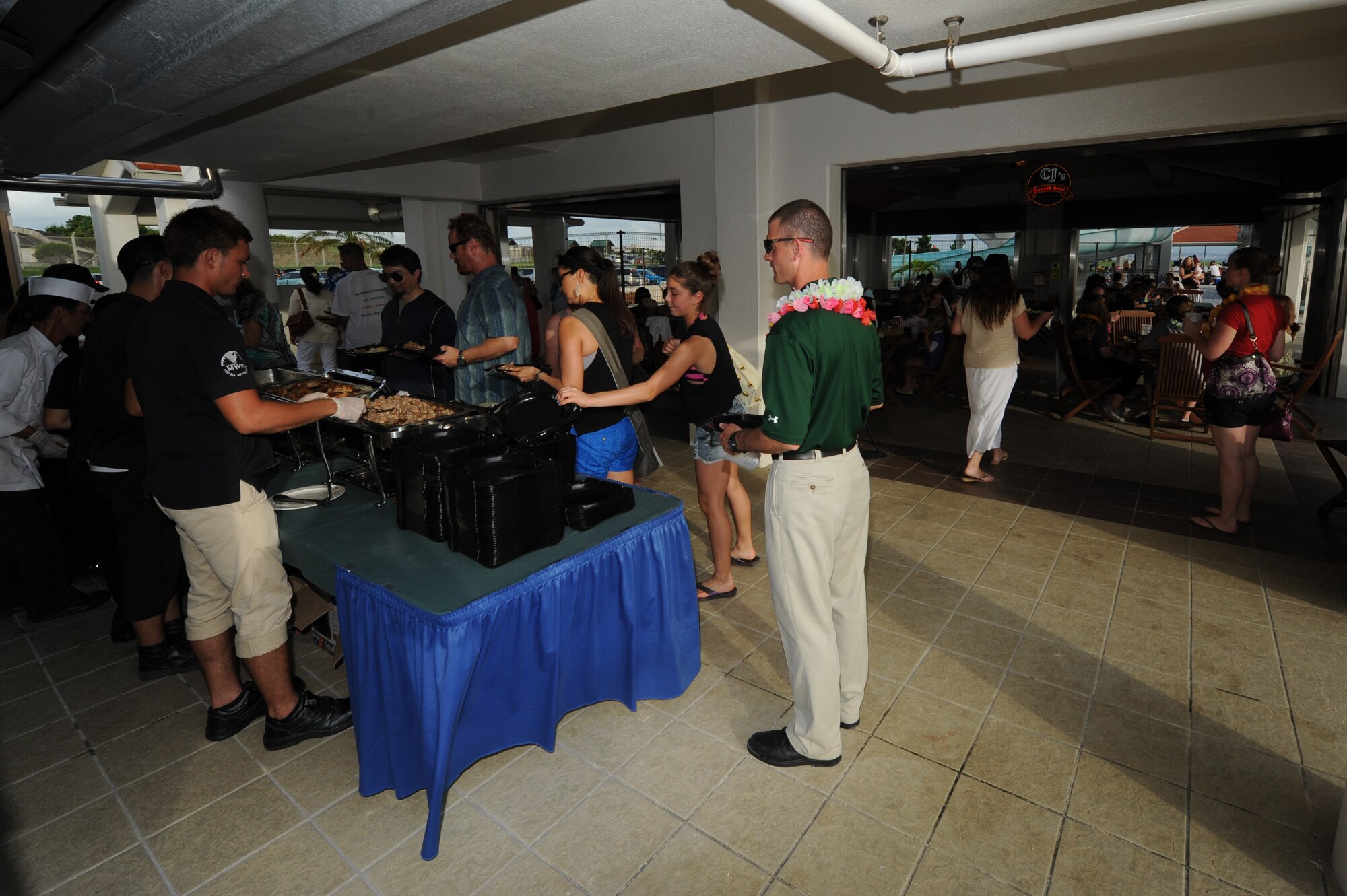 Volunteers from the Moral, Welfare, and Recreation center serve pork, grilled chicken, fried rice, pizza, and other food items to the attendees of the Deployed Spouses Luau on Torii Beach, Japan, June 21, 2014. More than 170 people and more than 20 commanders, chiefs, and first sergeants attended the luau. (U.S. Air Force photo by Airman 1st Class Stephen G. Eigel)