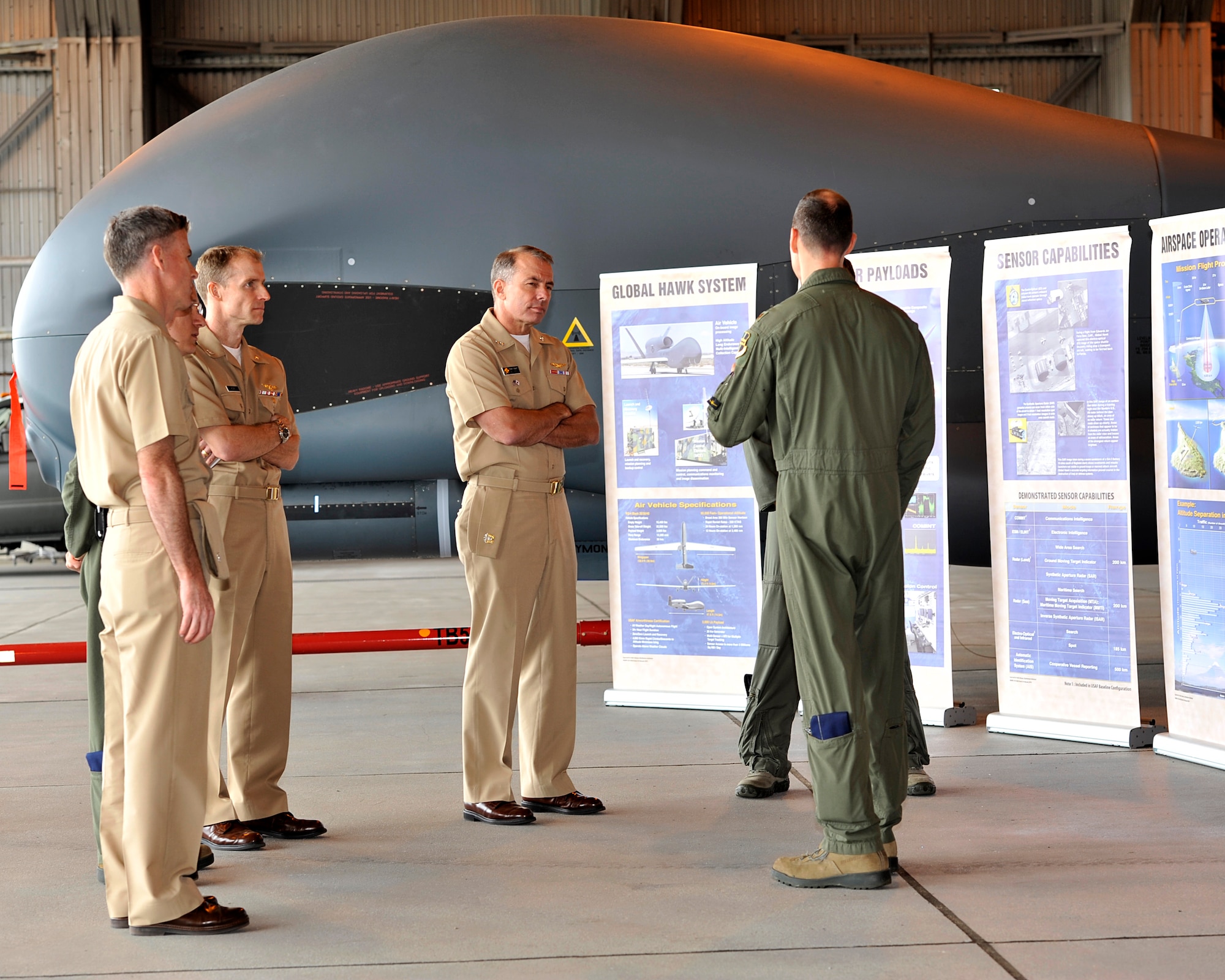 Rear Adm. Terry Kraft, center, U.S. Naval Forces Japan commander, listens as 69th Reconnaissance Group Detachment 1 leadership explains some of the capabilities of the RQ-4 Global Hawk unmanned aerial vehicle (UAV) surveillance aircraft, June 19, 2014. Kraft is currently visiting NAF Misawa, and is using the opportunity to meet with Sailors, and to inspect the installation’s various facilities. (U.S. Navy photo by Senior Chief Mass Communication Specialist Daniel Sanford/Released)