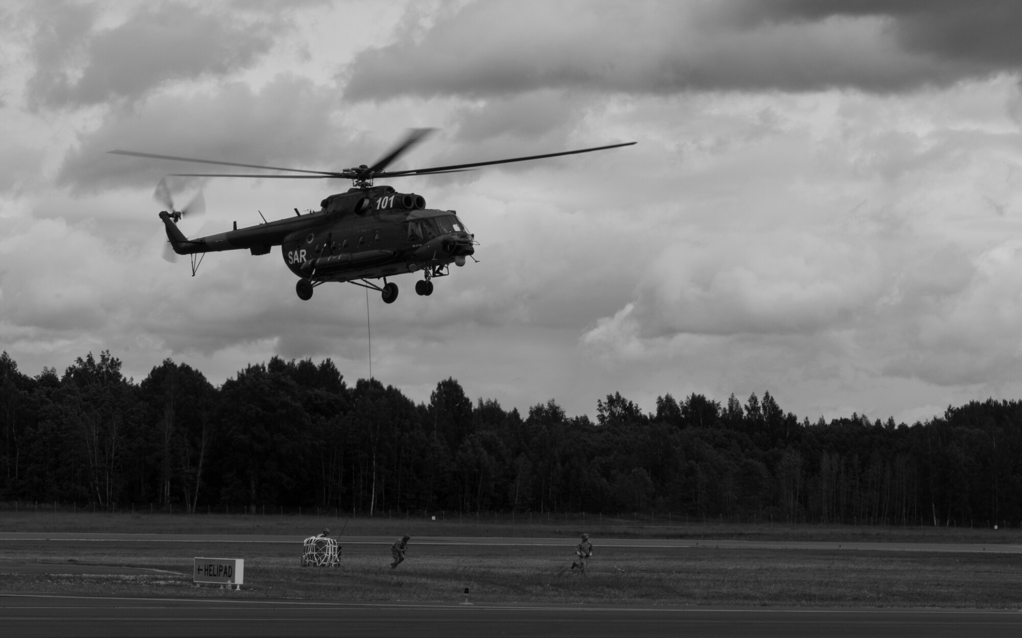 Airmen from the 435th Contingency Response Group clear the area after attaching a bundle onto a Latvian Mi-8 helicopter in part of sling-load operations training during the Air Force-specific portion of Saber Strike at Lielvarde Air Base, Latvia, June 17, 2014. During the final week of Saber Strike 2014 the 435th CRG, in conjunction with the 37th Airlift Squadron, trained on the full capabilities to open the Latvian air base. They also trained with Latvian and Estonian service members on airfield operations, command and control of air and space forces, weather support, and protection of operational forces, aircraft maintenance and aerial port services. (U.S. Air Force photo/Senior Airman Jonathan Stefanko)