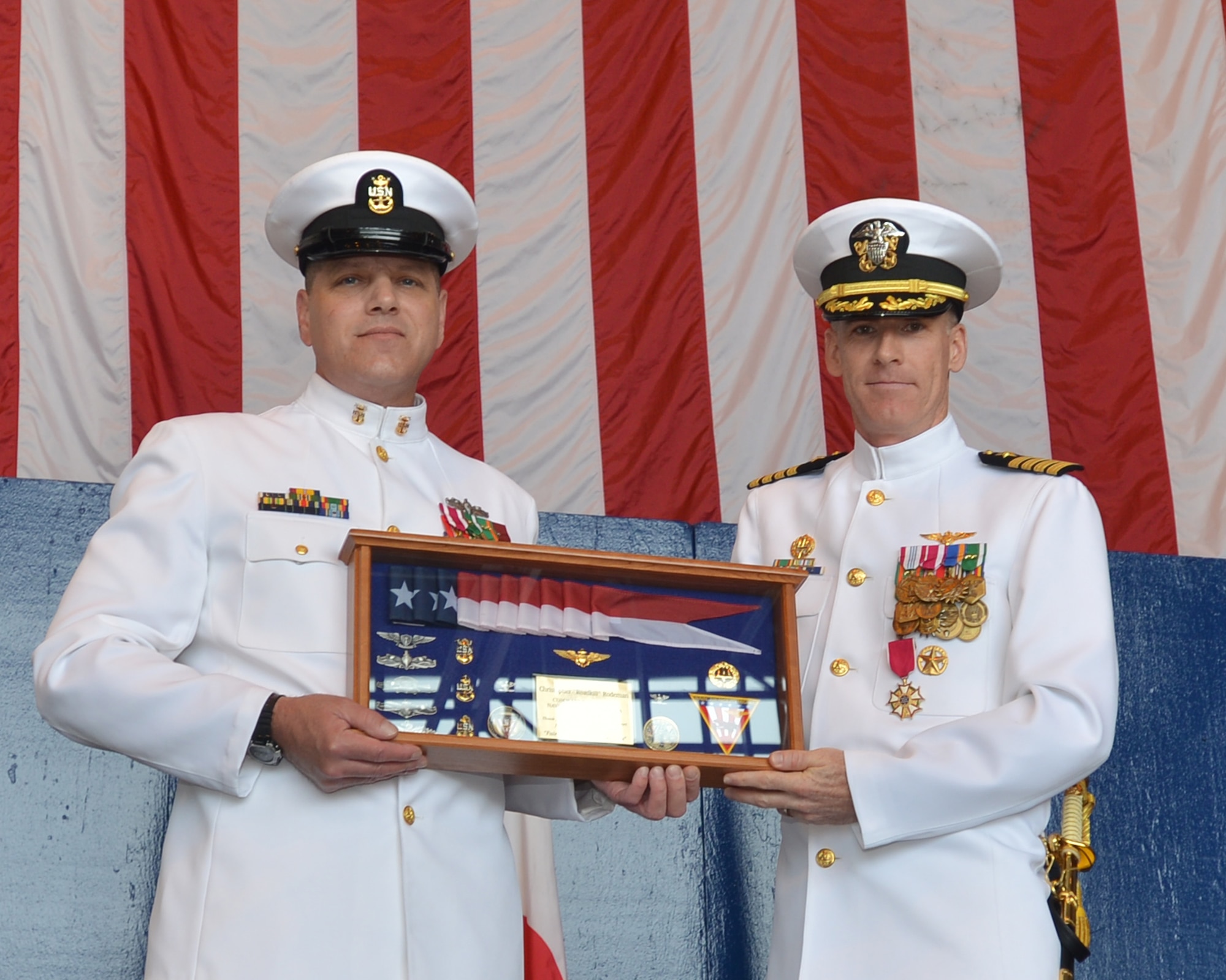 Naval Air Facility (NAF) Misawa Command Master Chief Scott Knorowski, left, originally from Jersey City, New Jersey, presents NAF Misawa Commanding Officer Capt. Chris Rodeman, a native of Anderson, Indiana, with a commissioning pennant box on behalf of the command’s chief mess, June 20, 0214.  Knorowski presented the gift during NAF Misawa's Change of Command Ceremony, in which Capt. Keith Henry assumed command from Rodeman. NAF Misawa is a U.S. naval installation located in northern Japan. (U.S. Navy photo by Mass Communication Specialist 3rd Class Erin Devenberg/Released)