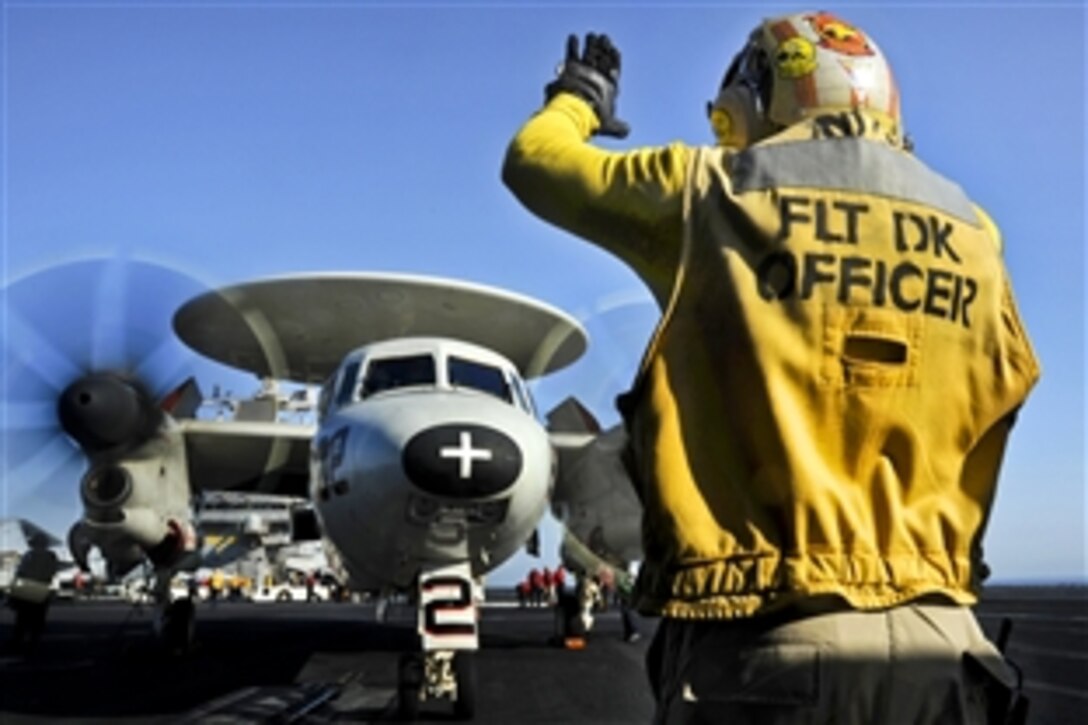 A U.S. sailor directs an E-2C Hawkeye aircraft on the flight deck of the aircraft carrier USS George H.W. Bush in the Persian Gulf, June 19, 2014. The Hawkeye is assigned to Carrier Airborne Early Warning Squadron 124. U.S. Defense Secretary Chuck Hagel previously ordered the carrier into the Persian Gulf to provide President Barack Obama additional flexibility should military options be required to protect American lives, citizens and interests in Iraq.