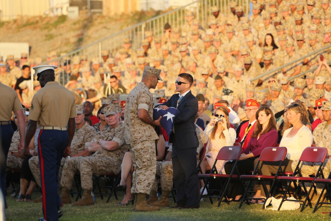 Sgt. Julio Vegaflores, reviewing officer, presents a flag to Cpl. William “Kyle” Carpenter, the most recent Medal of Honor recipient, during an evening colors ceremony aboard Marine Corps Air Station Miramar, Calif., June 23.
