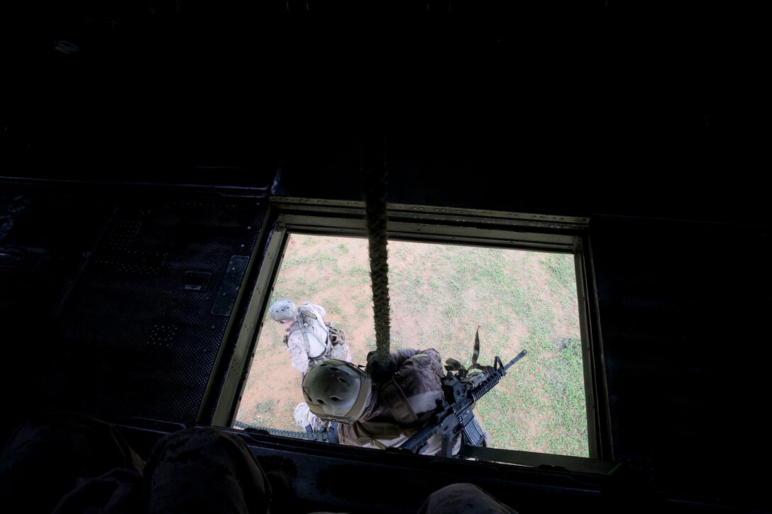 Marines with Force Reconnaissance Company, 3rd Reconnaissance Battalion, fast-rope out of the center of a CH-53E Super Stallion helicopter, fully equipped for combat June 17 at the Central Training Area near Camp Schwab. The training prepared Marines for an upcoming deployment with the 31st Marine Expeditionary Unit. The Marines are reconnaissance men with Force Recon Company, 3rd Recon Bn., 3rd Marine Division, III Marine Expeditionary Force. (U.S. Marine Corps photo by Lance Cpl. Brittany A. James/Released)