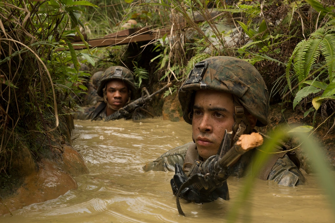 Cpl. Christian Hiraldo, right, leads his Marines and sailors through a mud pit during the jungle endurance course June 20 at the Jungle Warfare Training Center on Camp Gonsalves, Marine Corps Base Camp Smedley D. Butler, Marine Corps Installations Pacific. During the course, Marines and sailors were required to navigate the harsh jungle environment as well as man-made obstacles in the heat and humidity of Okinawa. Hiraldo is a Brooklyn, New York, native and rifleman with 1st Battalion, 8th Marine Regiment, which is currently assigned to 4th Marines, 3rd Marine Division, III Marine Expeditionary Force, under the unit deployment program. 