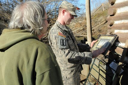 Army Spc. Timothy Copley, an infantryman with the West Virginia Army National Guard, picks up an unscathed picture from the ruins of resident, Janet Porterfields home March 5, 2012. Porterfield was trapped in her house for three days as National Guard Soldiers and Department of Highway workers struggled to clear fallen trees and debris out of the road.