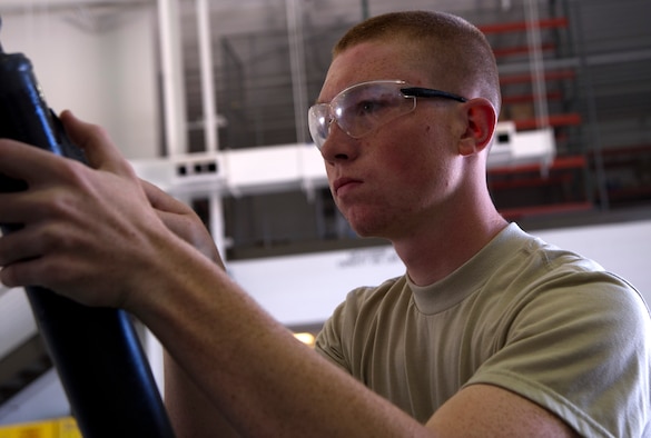 Airman 1st Class Tyler Graham sands the stickers of a 10 ton jack in preparation to be painted June 18, 2014, at Creech Air Force Base, Nev. The 423nd Maintenance Squadron aerospace ground equipment crew is responsible for more than 761 pieces of equipment for the MQ-1 Predator and MQ-9 Reaper remotely-piloted aircraft, both on home-station and at deployed locations. Graham is a 423rd MXS AGE mechanic. (U.S. Air Force photo/Airman 1st Class Christian Clausen)