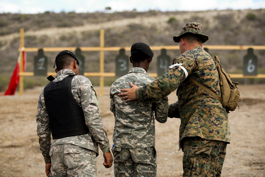 Cpl. John King-Kaplan, a fireteam leader with with Company C, 4th Law Enforcement Battalion, assists a member of the Dominican Republic's Army with an M4 Benelli Tactical Shotgun during range operations aboard Las Calderas Naval Base, Dominican Republic, June 21, 2014. U.S. Marines with C Co., 4th LE Bn., Force Headquarters Group, Marine Forces Reserve, and soldiers with the Canadian Army are training police forces and militaries from 13 partner nations participating in phase II of Tradewinds 2014 held from June 16 through June 25. Tradewinds 2014 is a joint, combined exercise conducted in order to improve partner nation counter-transnational organized crime missions and humanitarian aid and disaster response operations capacity. The exercise is also designed to promote interoperability and multinational relationships throughout the theater. (U.S. Marine Corps photo by Sgt. Jessica Ito/Released)