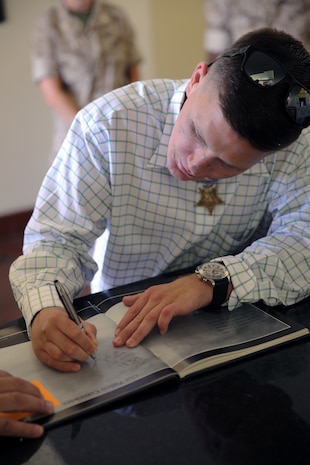 Corporal William K. Carpenter, Medal of Honor recipient, signs his name in a Medal of Honor book at the Command Museum aboard Marine Corps Recruit Depot San Diego, June 23. The book has the signatures of other Medal of Honor recipients as well.   