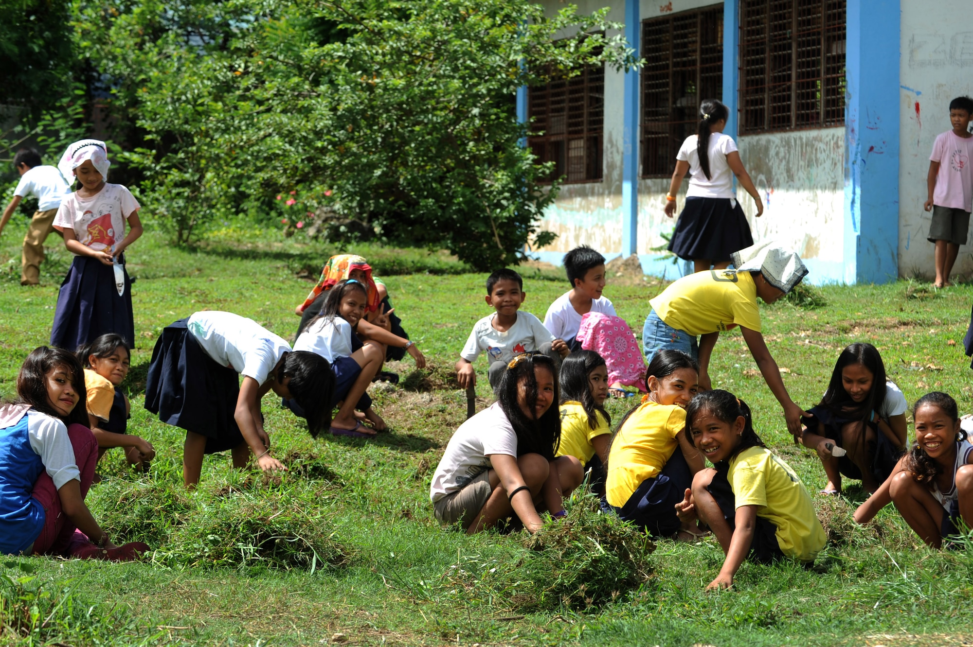Elementary students weed a playground area at Buyong Elementary School in Barangay Maribago, Lapu-Lapu City, Philippines June 18, 2014. The students cleaned the school grounds to prepare for the closing ceremony of Operation Pacific Unity 14-6. Pacific Unity is a bilateral Engineering Civic Action Program conducted in the Asia-Pacific region in collaboration with host nation military personnel. Airmen from the 374th CES spent 31 days building two classrooms and renovating utilities throughout the school. (U.S. Air Force photo by Staff Sgt. Amber E. N. Jacobs/Released)