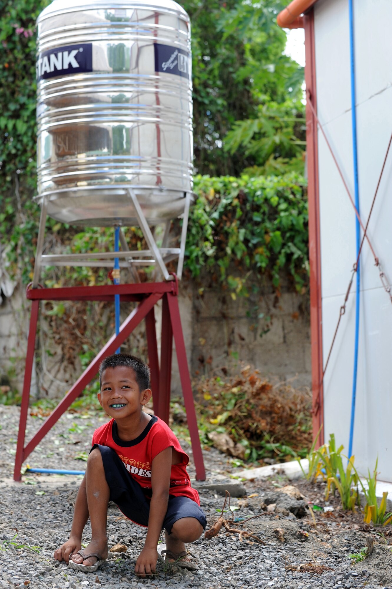 A student from Buyong Elementary school crouches in front of a new water catchment tank at Buyong Elementary School in Barangay Maribago, Lapu-Lapu City, Philippines June 18, 2014. Airmen from the 374th CES spent 31 days building two classrooms and renovating utilities throughout the school as part of a bilateral engineering program known as, Pacific Unity 14-6. One of the side projects the Airmen worked on was restoring running water to the school’s bathroom facilities. (U.S. Air Force photo by Staff Sgt. Amber E. N. Jacobs/Released)