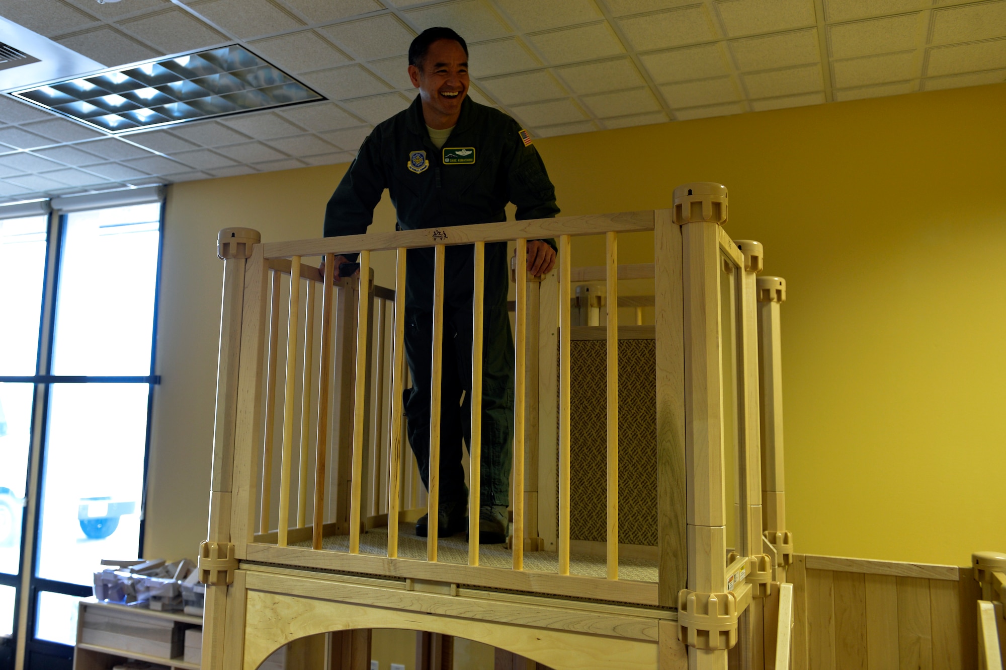 Col. David Kumashiro, 62nd Airlift Wing commander, tests the jungle gym in McChord Field’s new passenger terminal family lounge during a ribbon cutting ceremony June 23, 2014, at Joint Base Lewis-McChord, Wash. Aside from the play area, there was a common area featuring a large screen television, a quiet nursing room, a kitchen, gaming room, and a business center. (U.S. Air Force photo/Staff Sgt. Russ Jackson)