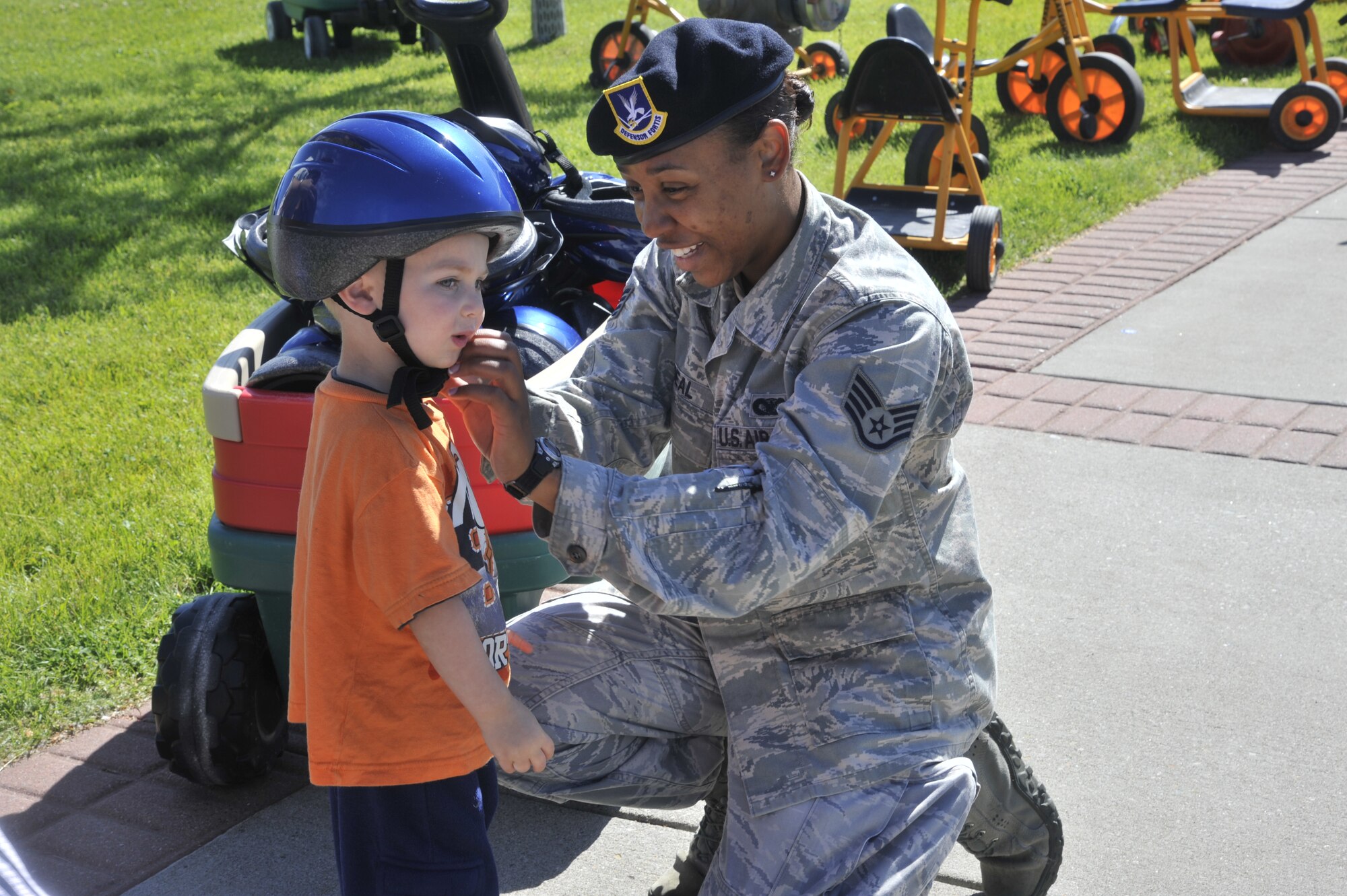 Staff Sgt. Denine Deal helps a student put on his helmet at the Fairchild Air Force Base, Wash., Child Development Center, June 20, 2014. Deal spoke with children about bicycle safety and proper protective gear to wear while riding a bike. Deal is the 92nd Security Forces Squadron police services NCO in charge. (U.S. Air Force photo by Senior Airman Mary O'Dell/Released)