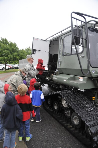 Vehicle operators from the 336th Training Support Squadron help children climb into a Tucker Terra at Fairchild Air Force Base, Wash., June 18, 2014. The Tucker is used to transport Survival, Evasion, Resistance and Escape students up to and around the woods when it is either too cold or they have to travel too far between training sites. (U.S. Air Force photo by Senior Airman Mary O'Dell/Released)