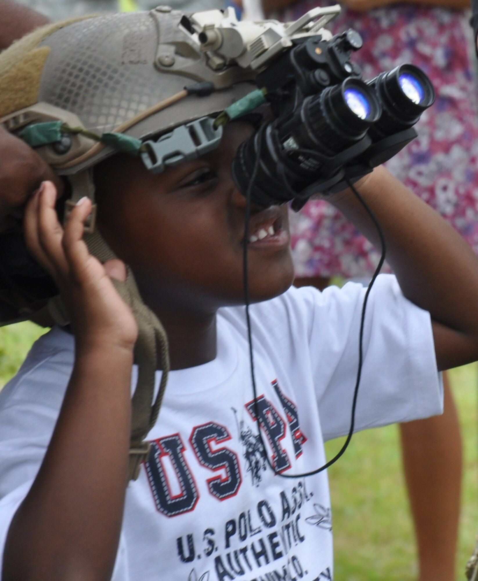 Xzavier White, 4, tries on an advanced combat helmet with night vision goggles at the 7th Special Forces Group (Airborne) headquarters on Eglin's range June 24. The 7th SFG (A) invited members of the Northwest Florida community onto their Compound for the Red Empire Community Day. The day's events featured recognition of the Group's distinguished volunteers and a parachute demonstration by the U.S. Special Operations Command Para-Commandos.  After the opening ceremony, attendees visited displays manned by Group soldiers to learn more about the 7th SFG (A), its soldiers and its missions. (U.S. Air Force photo/Chrissy Cuttita)