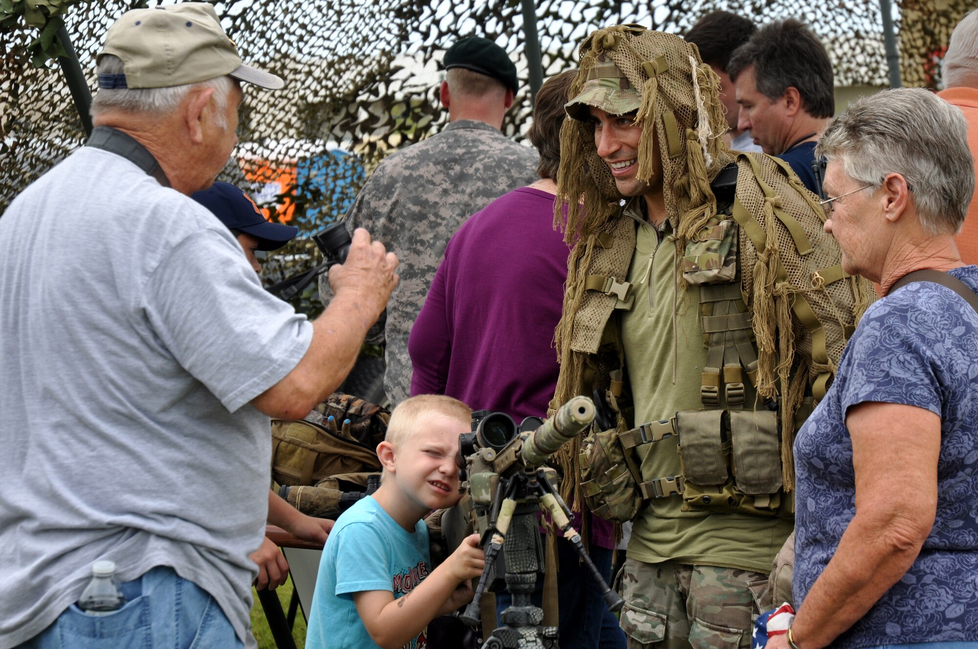 Army Staff Sgt. Travis Roberts tells visitors about the newest sniper rifles used in combat at the 7th Special Forces Group (Airborne) headquarters on Eglin's range June 24. The 7th SFG (A) invited members of the Northwest Florida community onto their Compound for the Red Empire Community Day. The day's events featured recognition of the Group's distinguished volunteers and a parachute demonstration by the USSOCOM Para-Commandos.  After the opening ceremony, attendees visited displays manned by Group soldiers to learn more about the 7th SFG (A), its soldiers and its missions. (U.S. Air Force photo/Chrissy Cuttita)