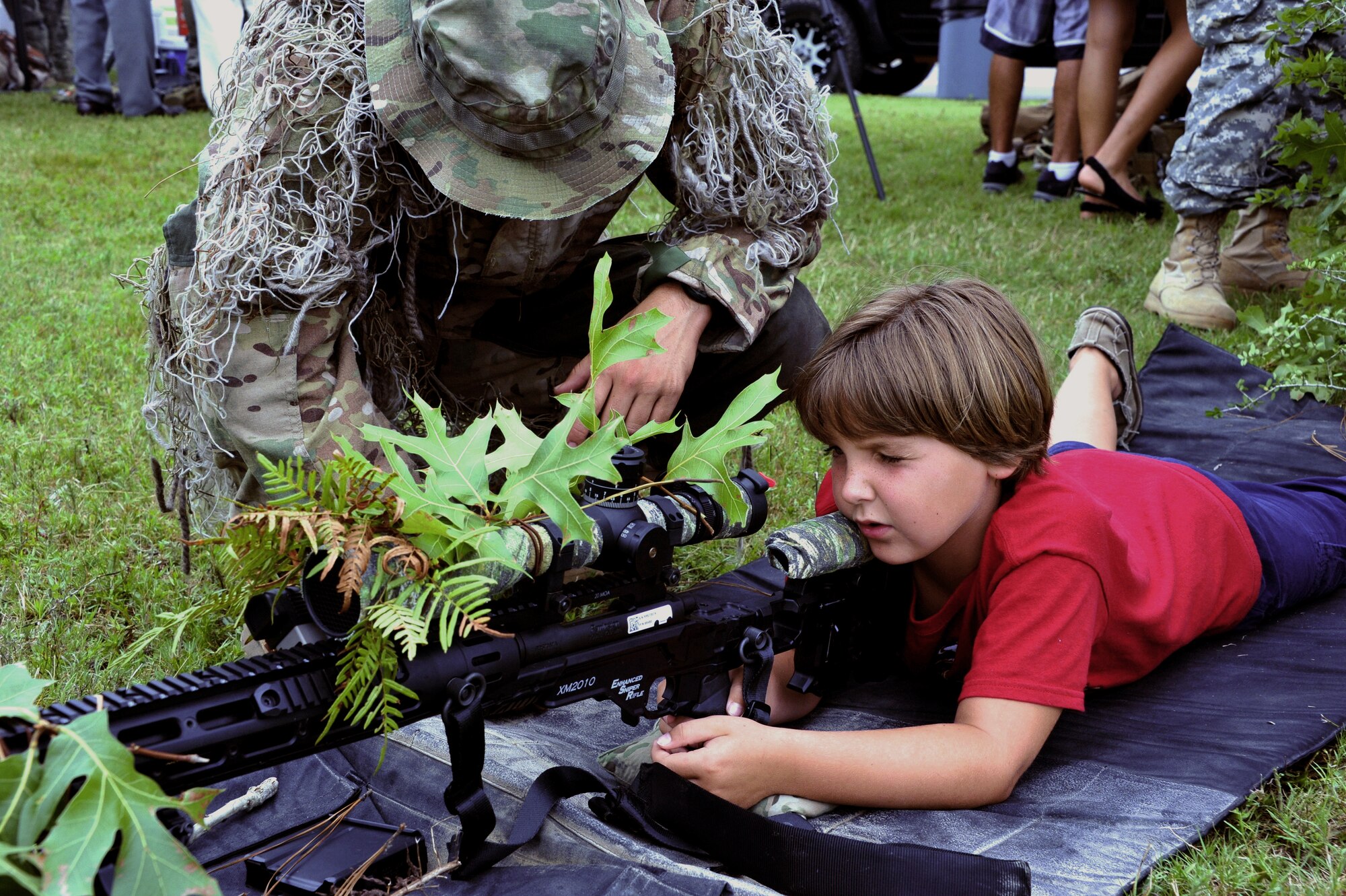 Wiley Adams, 6, learns about sniper rifles at the 7th Special Forces Group (Airborne) headquarters on Eglin's range June 24. The 7th SFG (A) invited members of the Northwest Florida community onto their Compound for the Red Empire Community Day Tuesday.  The day's events featured recognition of the Group's distinguished volunteers and a parachute demonstration by the USSOCOM Para-Commandos.  After the opening ceremony, attendees visited displays manned by Group soldiers to learn more about the 7th SFG (A), its soldiers and its missions. (U.S. Air Force photo/Ilka Cole)
