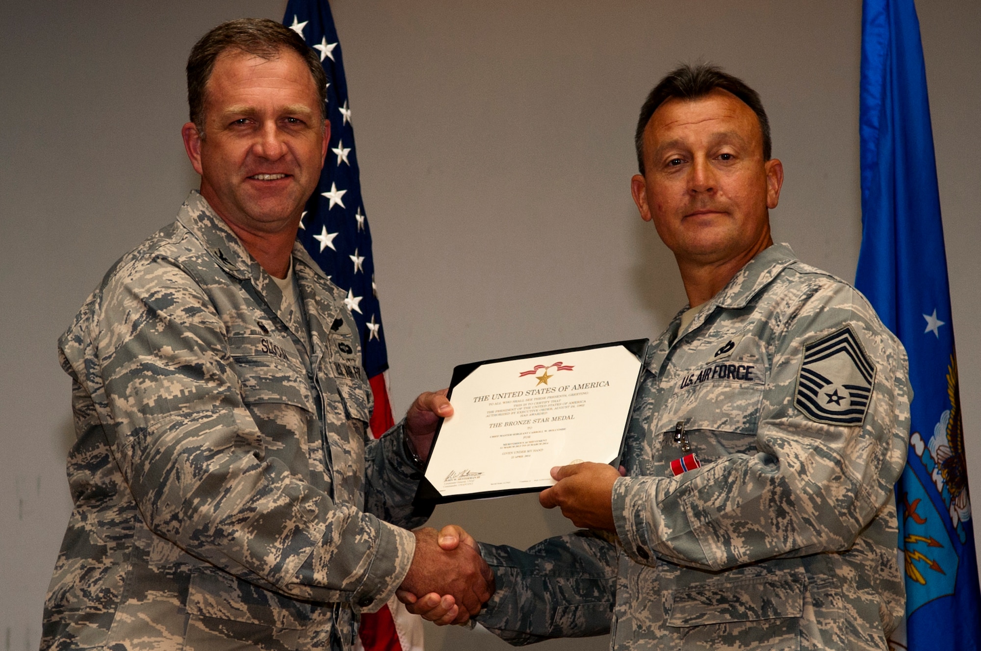 Col. Mark Slocum, 4th Fighter Wing commander, left, presents Chief Master Sgt. Carroll Holcombe, 4th CES superintendent with the Bronze Star medal, June 23, 2014, at Seymour Johnson Air Force Base, North Carolina. Holcombe received the medal for his actions while serving as superintendent of the 376th Expeditionary Mission Support Group at Transit Center at Manas, Kyrgyzstan. (U.S. Air Force photo/Airman 1st Class Shawna L. Keyes)