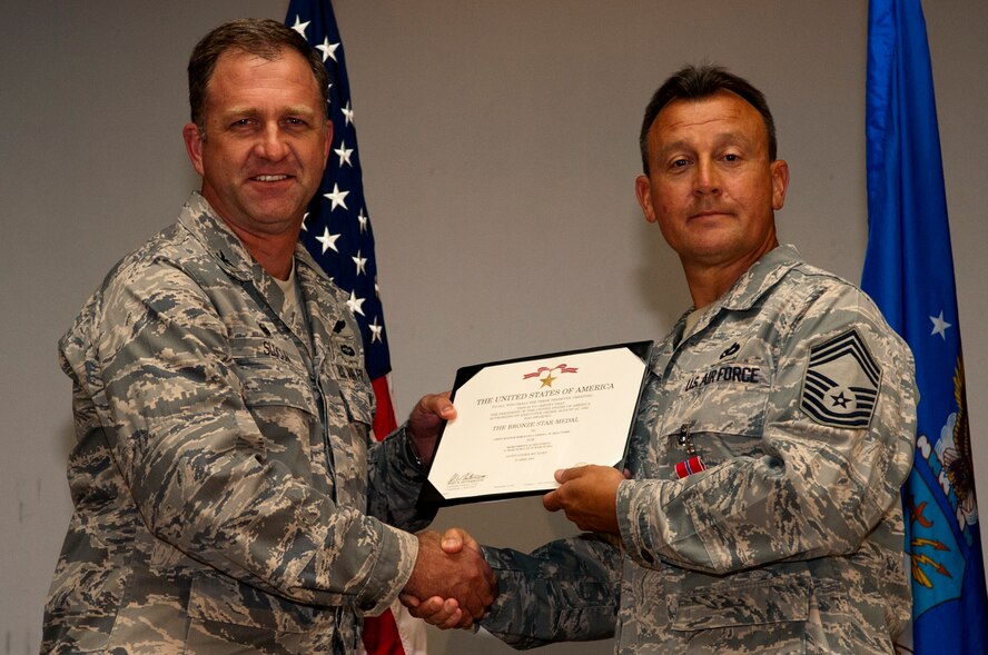 Col. Mark Slocum, 4th Fighter Wing commander, left, presents Chief Master Sgt. Carroll Holcombe, 4th Civil Engineer Squadron  superintendent with the Bronze Star medal, June 23, 2014, at Seymour Johnson Air Force Base, North Carolina. Holcombe received the medal for his actions while serving as superintendent of the 376th Expeditionary Mission Support Group at Transit Center at Manas, Kyrgyzstan. (U.S. Air Force photo/Airman 1st Class Shawna L. Keyes