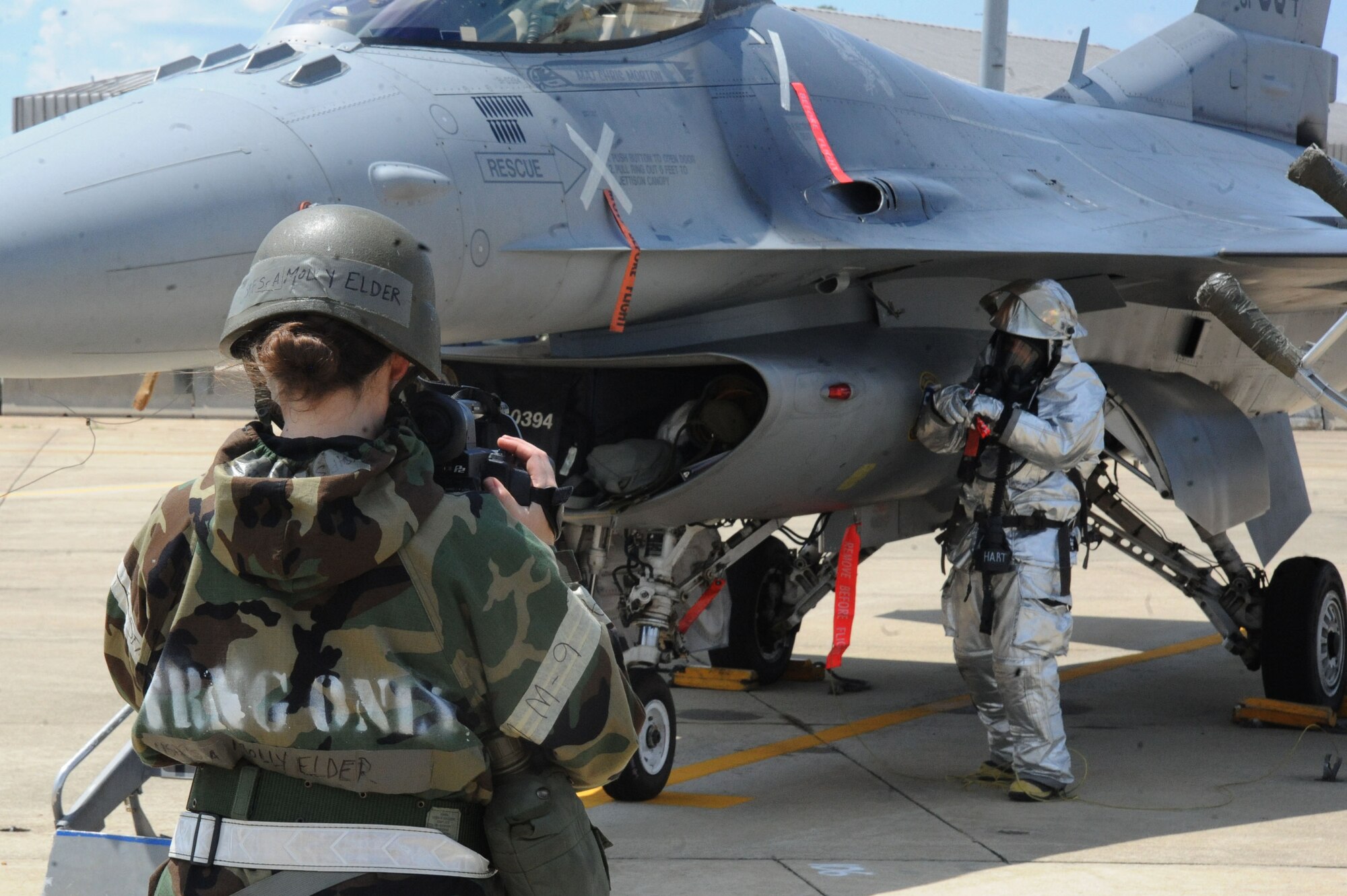 U.S. Air Force Senior Airman Molly Elder, 20th Public Affairs broadcast journalist, takes video of 20th Civil Engineer Squadron fire fighters simulating the rescue of a pilot from an F-16CJ Fighting Falcon at Shaw Air Force Base, June 23, 2014. The mission of broadcast journalism is to cover Air Force history via motion media while at home or deployed. (U.S. Air Force photo by Airman 1st Class Michael A. Cossaboom)