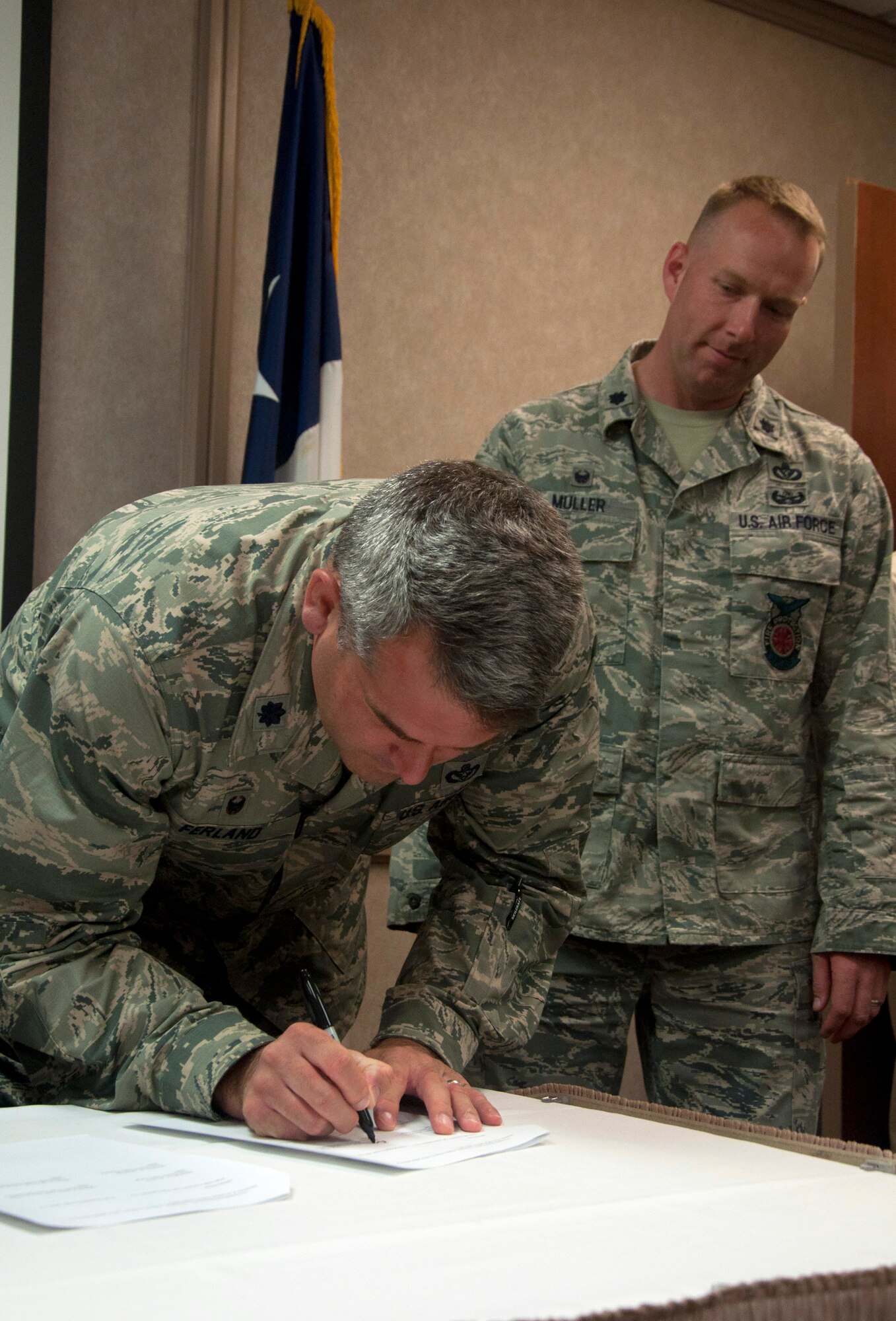 SAN ANGELO, Texas--Lt. Col. Kurt E. Muller, 17th Civil Engineer Squadron Commander, observes Lt. Col. Derek R. Ferland, 312th Training Squadron Commander, signing one of four original copies of the memorandum of understanding at the Angelo State University’s Houston Harte Center June 12. The MOU allows Tom Green County officials to participate in training as well as utilize facilities on base involving emergency management. The plans are a part of the Air Force Community Partnership Initiative. (U.S. Air Force photo/ Master Sgt. Jennifer Redente)