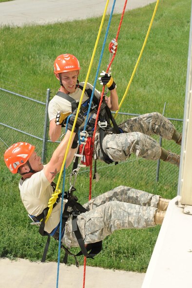 U.S. Army Spc. Ryan Krogstad, South Dakota National Guard 451st Engineer detachment pumper operator, (left) rappels from a building with the help of Senior Airman Kyle Brown, 28th Civil Engineer Squadron driver operator, during a Golden Coyote training exercise at Ellsworth Air Force Base, S.D., June 17, 2014. Airmen and SDNG Soldiers participated in high rescue training to learn rappel and reconnaissance techniques to rescue victims that have been trapped in various locations. (U.S. Air Force photo by Airman 1st Class Rebecca Imwalle/ Released)