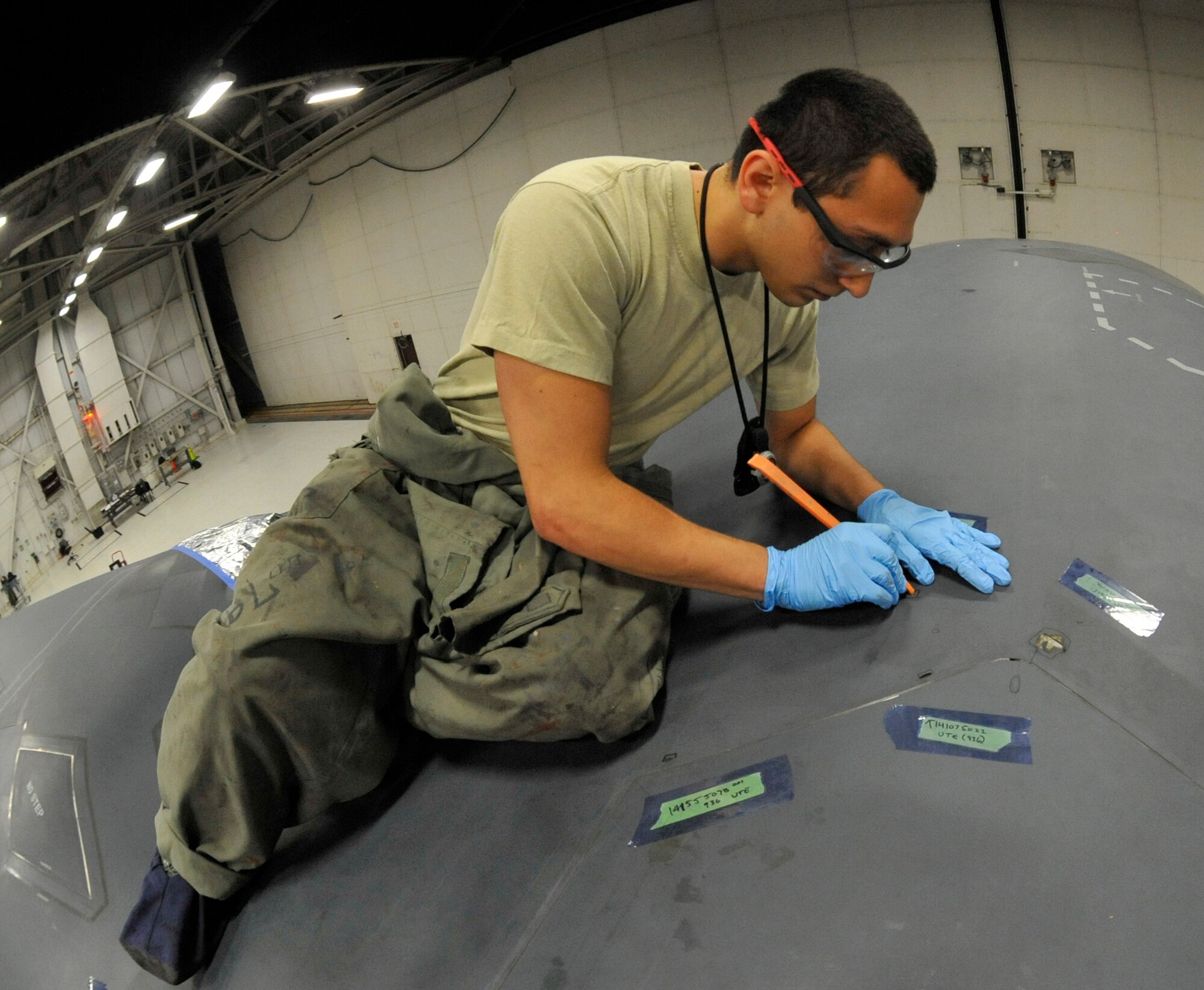 Senior Airman Alexander Ramirez, 509th MXS Low Observable aircraft structural maintainer, inspects thin tape in the B-2 Spirit’s arrsi door at Whiteman Air Force Base, Mo., June 12, 2014. If the tape reaches a certain point of negligible damage, it must be removed and replaced. (U.S. Air Force photo by Airman 1st Class Keenan Berry/Released)