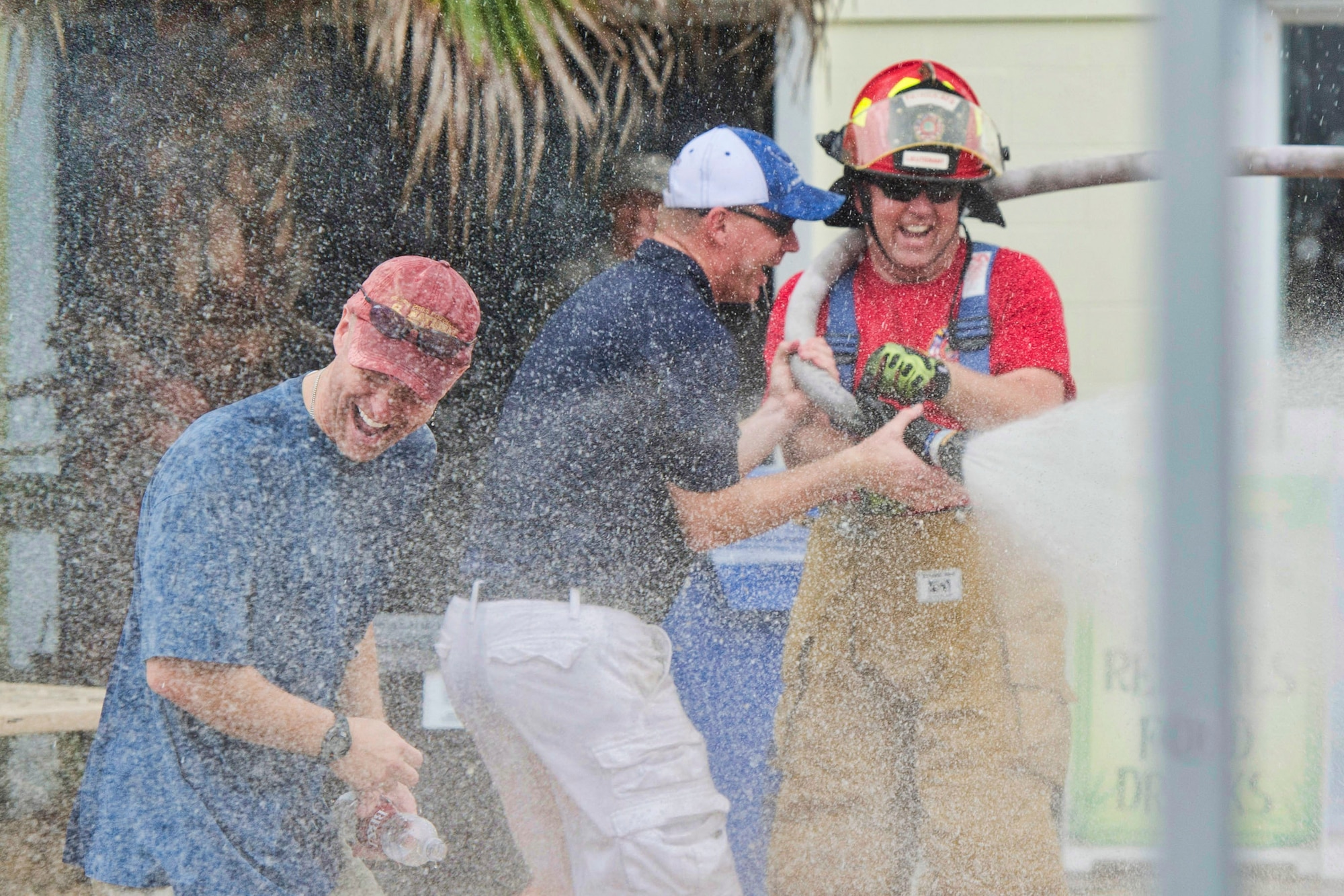 Gene Carlander, 45th Civil Engineer Squadron, sprays Col. Robert Pavelko, 45th Space Wing vice commander (left), and Chief Master Sgt. Craig Neri, 45th Space Wing command chief (center), during the Junior Enlisted Appreciation Picnic June 20 at the Patrick Air Force Base, Fla., Beach House. Senior leadership was drenched with water by junior enlisted members as part of a tradition after opening remarks. (U.S. Air Force photo/Matthew Jurgens) 