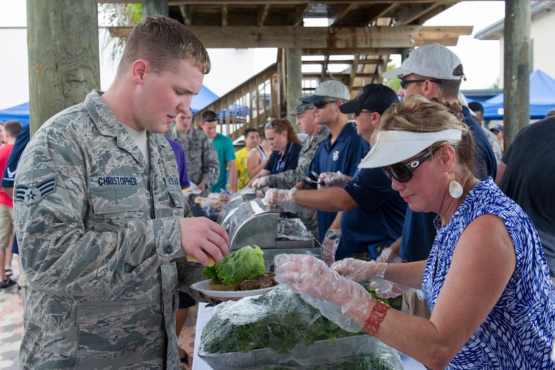 Senior Airman Justin Christopher, Air Force Technical Applications Center, receives lettuce from a volunteer during the Junior Enlisted Appreciation Picnic June 20 at the Patrick Air Force Base, Fla., Beach House. The Patrick AFB Top 3 and the Military Affairs Committee hosted the event which was open to all military services E-6 and below. (U.S. Air Force photo/Matthew Jurgens)