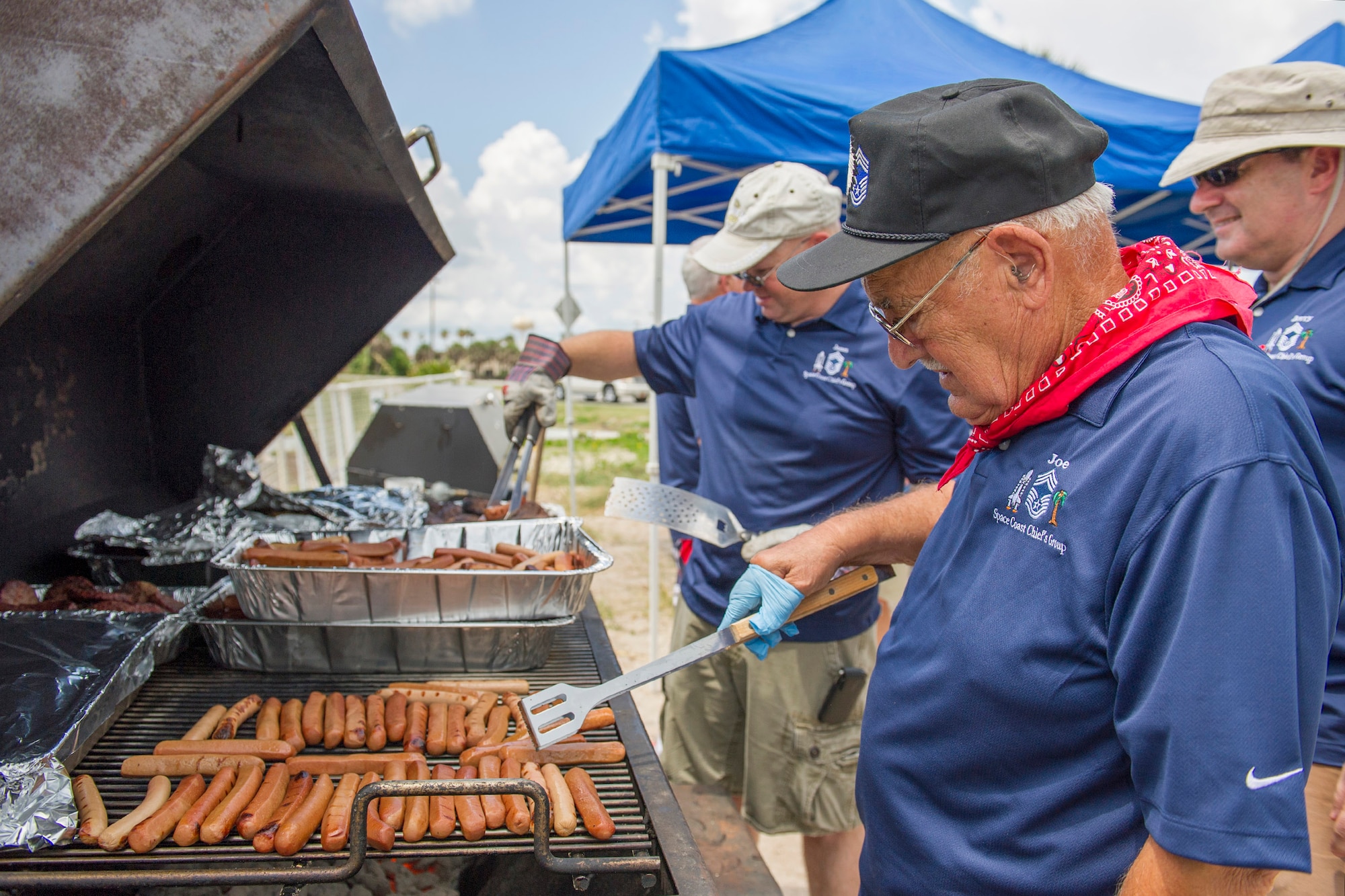 Retired Chief Master Sgt. Joe Pannitto, Chief Master Sgt. James Isom, 45th Operations Group (back left), and, Chief Master Sgt. Gerald “Jerry” McFadden, Air Force Technical Applications Center (back right), grill hot dogs during the Junior Enlisted Appreciation Picnic June 20 at the Patrick Air Force Base, Fla., Beach House.  The Patrick AFB Top 3 and the Military Affairs Committee hosted the event which was open to all military services E-6 and below. (U.S. Air Force photo/Matthew Jurgens)