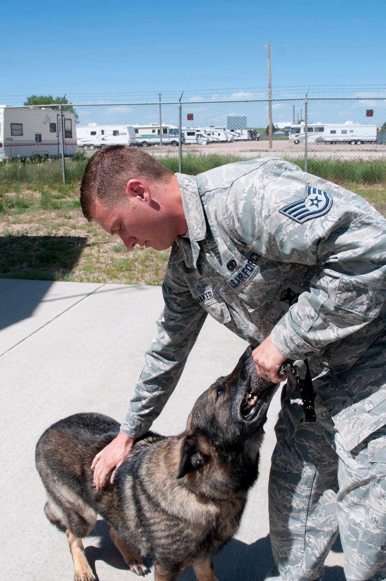Staff Sgt. Stephen Showmaker, 90th Security Forces Squadron military working dogs handler, plays with Kichi outside of the MWD kennel on F.E. Warren Air Force Base, Wyo., June 17. Kichi was retired due to his night blindness and back issues. (U.S. Air Force photo by Airman Malcolm Mayfield)