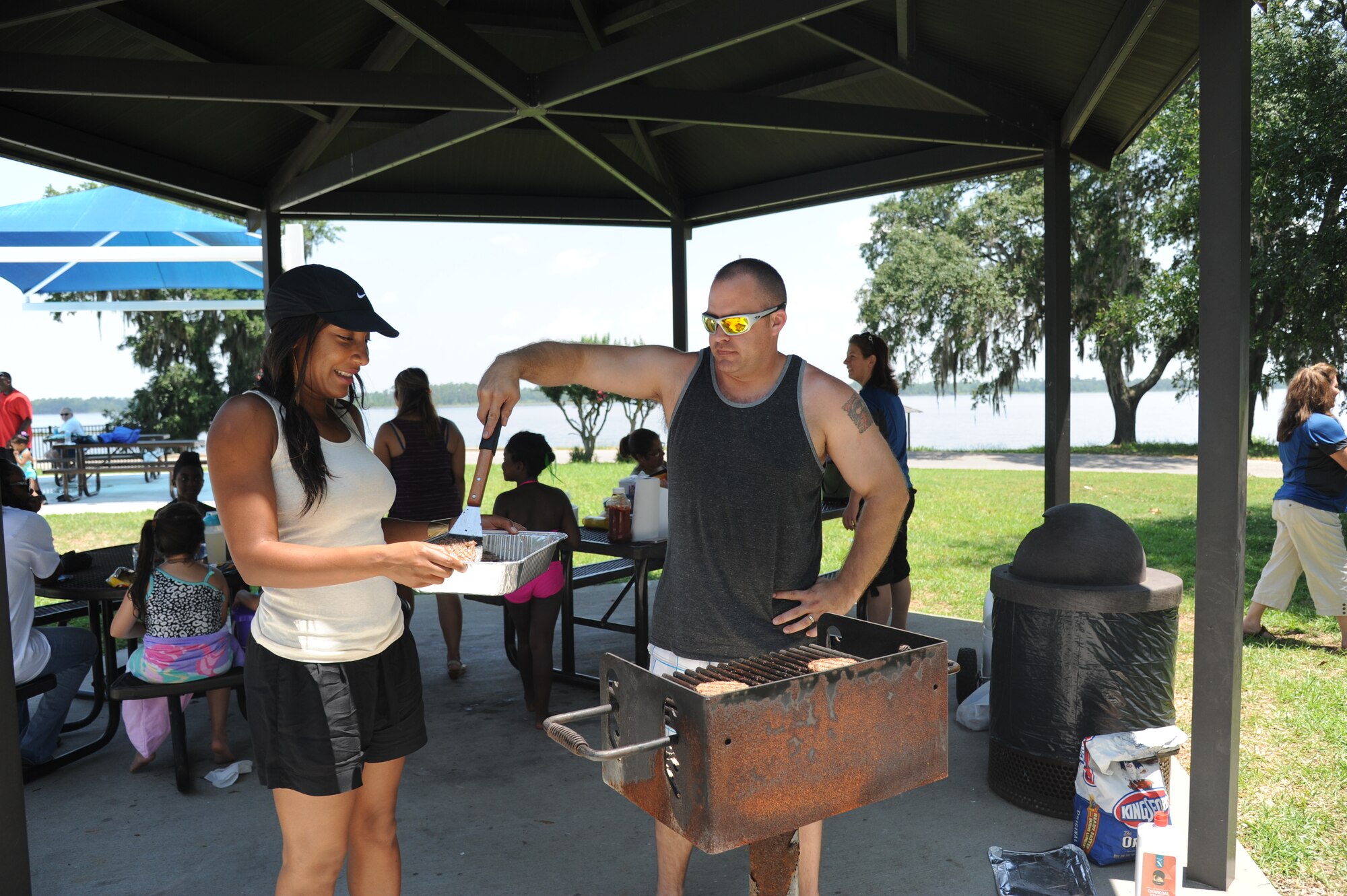 Master Sgts. Tomeika Frazier and Marcus Hogsten, 81st Force Support Squadron, grill hamburgers during a deployed family picnic June 21, 2014, at the marina, Keesler Air Force Base, Miss.  The event, sponsored by the Airmen and Family Readiness Center, also included games and playtime on the splash pad.  (U.S. Air Force photo by Kemberly Groue)