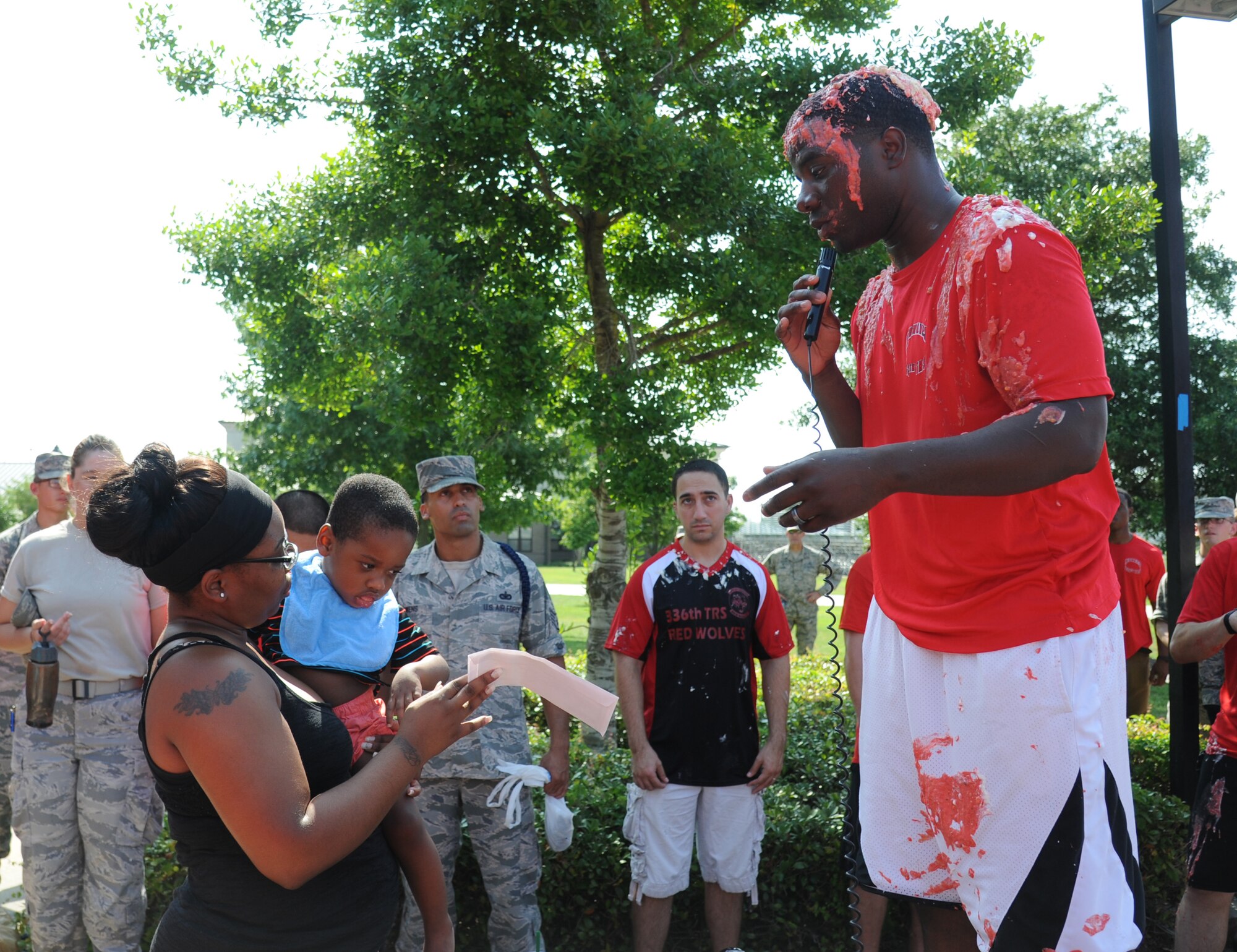 Staff Sgt. L.C. Fowler, 336th Training Squadron military training leader, presents a check to Uaketha Bonner and her son, Elijah Bonner, during a squadron fundraiser June 20, 2014, at the triangle, Keesler Air Force Base, Miss.  The squadron raised more than $1,500 to assist with the purchase of a walker for Elijah.  (U.S. Air Force photo by Kemberly Groue)