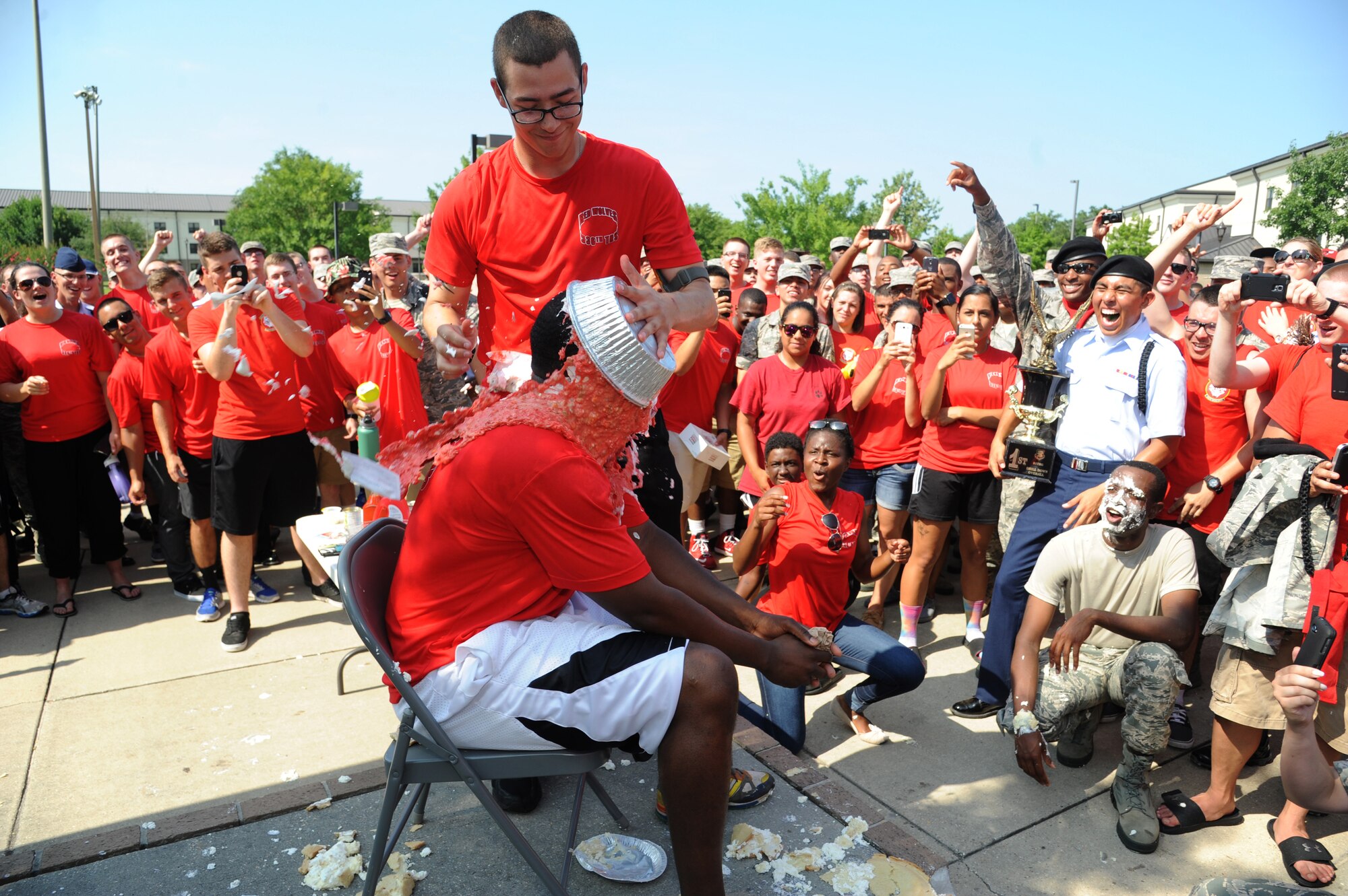 Airman 1st Class Joseph Craft, 336th Training Squadron, dumps a “specially made” pie on the face of Staff Sgt. L.C. Fowler, 336th TRS military training leader, during a squadron fundraiser June 20, 2014, at the triangle, Keesler Air Force Base, Miss.  The squadron raised more than $1,500 to assist with the purchase of a walker for a local boy.  (U.S. Air Force photo by Kemberly Groue)