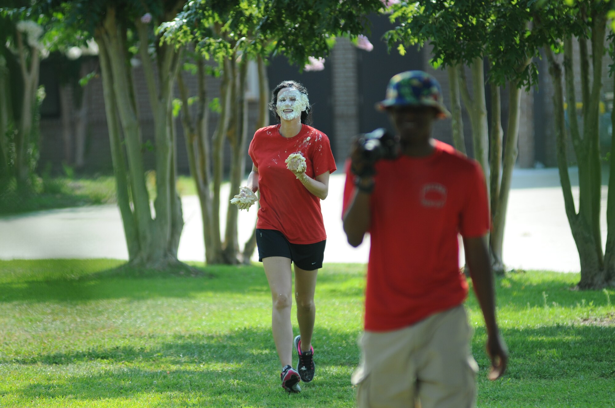 Staff Sgt. Kirsten Wong, 336th Training Squadron, runs with hands full of pie after receiving a pie-in-the-face, in search of the Airman responsible during a squadron fundraiser June 20, 2014, at the Triangle, Keesler Air Force Base, Miss.  The squadron raised more $1,500 to assist with the purchase of a walker for a local boy.  (U.S. Air Force photo by Kemberly Groue)