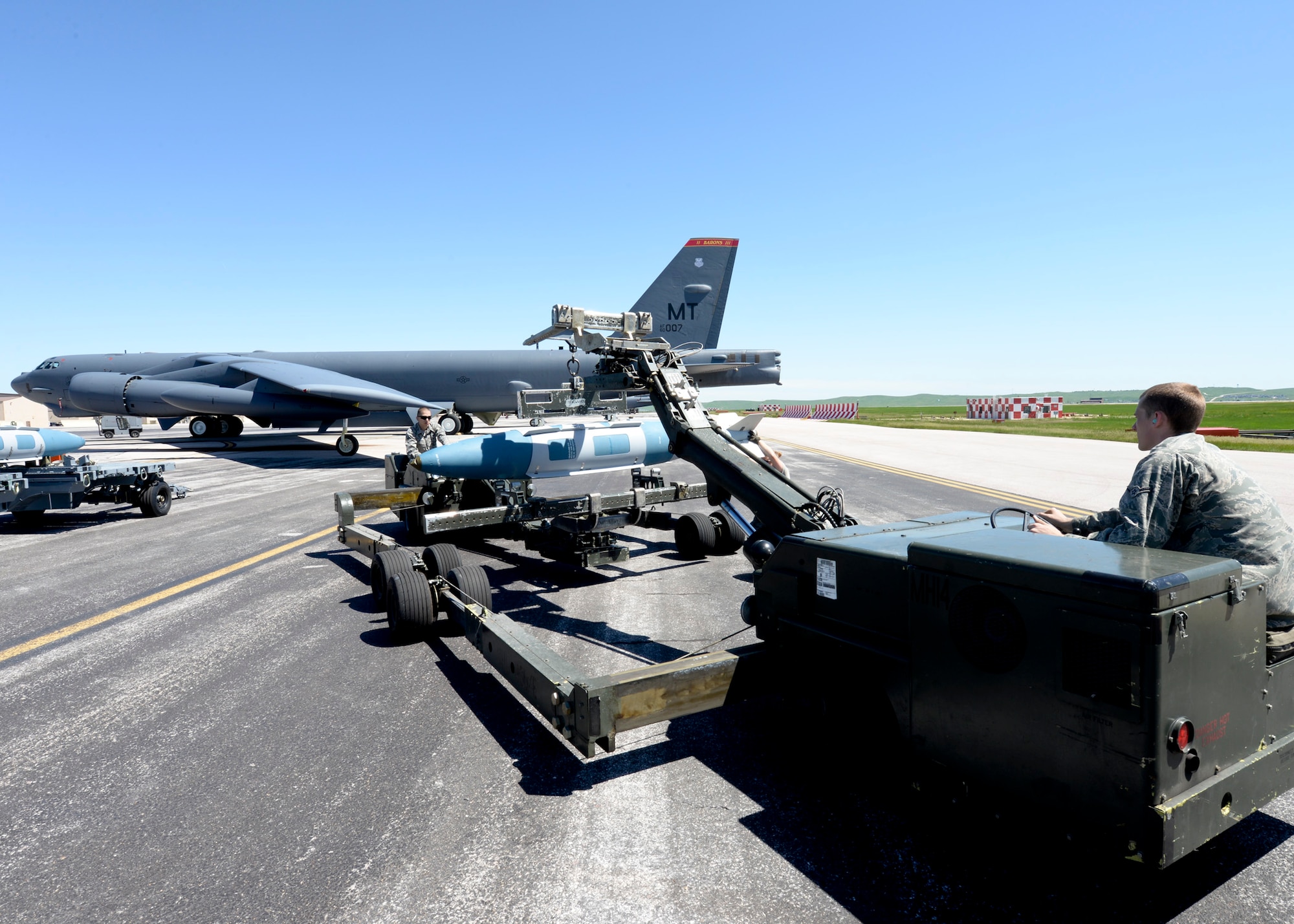 Airman 1st Class Dustin Lumpkin and Airman Michael Page, 5th Aircraft Maintenance Squadron weapons load crew members, transport a GBU-31 onto a B-52 Stratofortress at Ellsworth Air Force Base, S.D., June 9, 2014. It takes six weeks for weapons load crew members to become certified on controlling, maintaining and installing aircraft bombs. (U.S. Air Force photo by Senior Airman Anania Tekurio/Released)