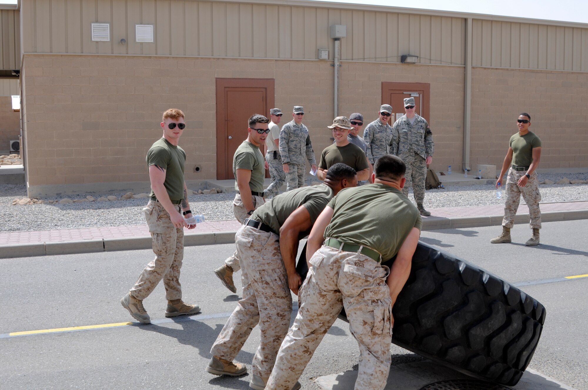 Two U.S. Marines assigned to 2nd Law Enforcement Battalion, USCENTCOM Regional Customs, battle against the clock during a tire flip exercise as a part of the Battle of the Badges held June 21, 2014. Military members who wear a badge for military police, fire department or explosive ordinance disposal competed against other military members in multiple events including a ruck march, MRAP pull and relay race to earn the title of best badge wearer. (U.S. Air Force photo by 1st Lt. Holli Nelson)