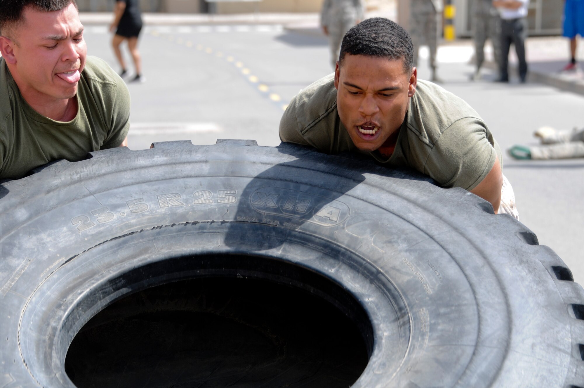 Two U.S. Marines assigned to 2nd Law Enforcement Battalion, USCENTCOM Regional Customs, battle against the clock during a tire flip exercise as a part of the Battle of the Badges held June 21, 2014. Military members who wear a badge for military police, fire department or explosive ordinance disposal competed against other military members in multiple events including a ruck march, MRAP pull and relay race to earn the title of best badge wearer. (U.S. Air Force photo by 1st Lt. Holli Nelson)