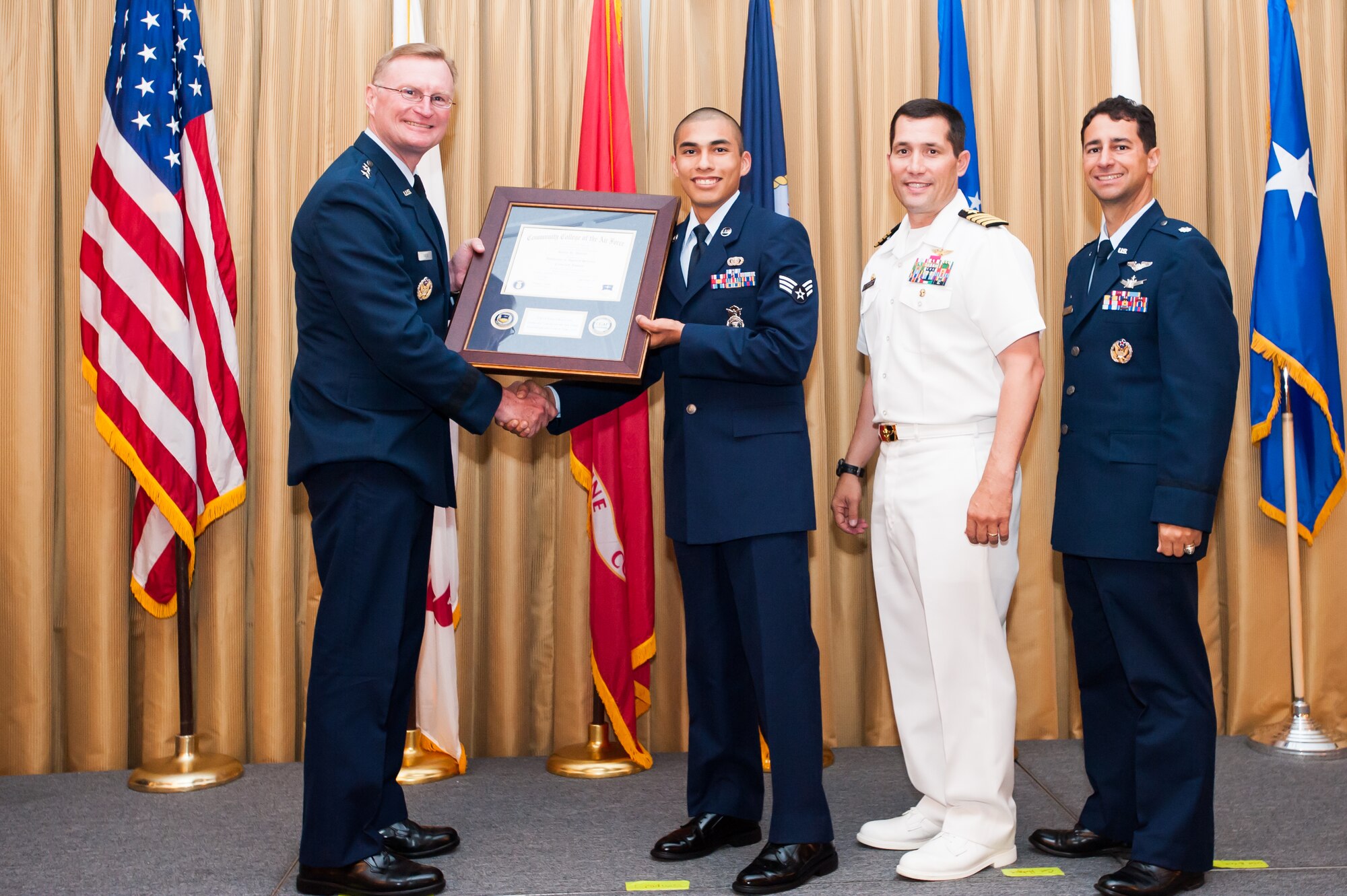 U.S. Air Force Lt. Gen. David Fadok, president and commander U.S. Air Force Air University, presents a framed diploma and coins to Senior Airman Kevin Duran, 421st Combat Training Squadron contingency skills instructor, for being the 350,000th graduate of the Community College of the Air Force. Duran majored in criminal justice and is working on a second associate degree in instructor technology and military science. Also present were U.S. Navy Capt. Christopher Fletcher, deputy commander Joint Base McGuire-Dix-Lakehurst and commanding officer Naval Support Activity-Lakehurst, and Lt. Col. Michael Artelli, commandant CCAF. (U.S. Air Force photo by John Sidoriak)