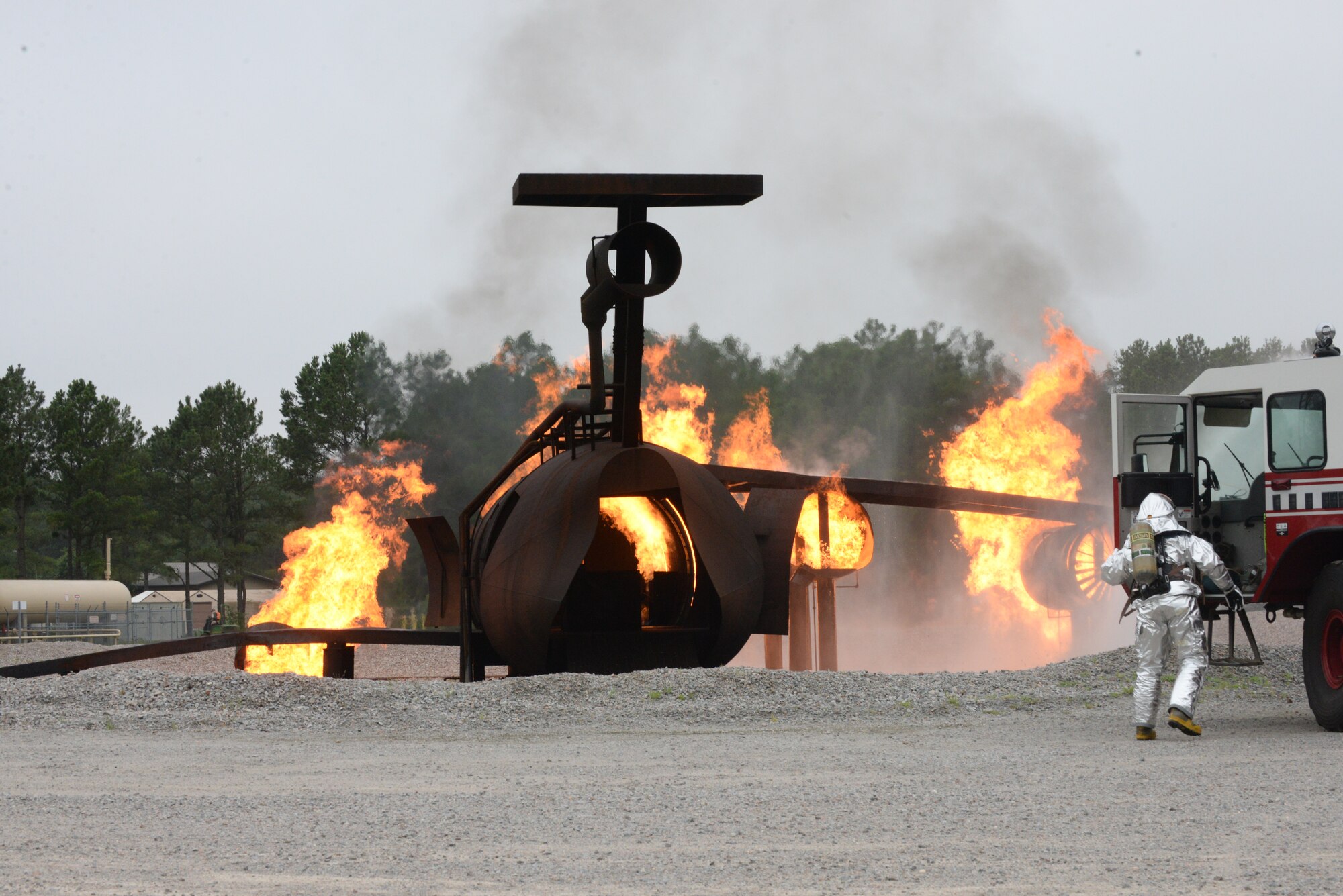 An Airman exits a fire truck and prepares to put out a simulated aircraft fire during an operational readiness exercise at Shaw Air Force Base, S.C., June 23, 2014. The ORE is a method of ensuring Airmen are prepared to respond to challenges they may face in a deployed environment. (U.S. Air Force photo by Airman 1st Class Michael A. Cossaboom/Released)
