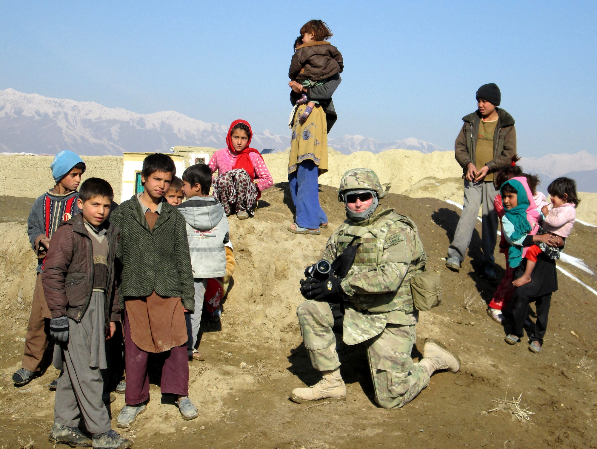 Senior Airman Chris Willis gathers with local Afghan children after documenting a tribal council meeting in a village outside of Bagram Airfield, Afghanistan, January 26, 2013. (courtesy photo)