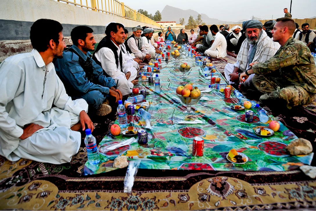 U.S. Air Force 1st Lt. Mark Graff relaxes with Afghan officials during an iftar dinner hosted by Provincial Reconstruction Team Farah for provincial government and Afghan officials on Forward Operating Base Farah in Afghanistan's Farah province, Aug. 28, 2011. Iftar is a meal to break the sunrise to sunset fast Muslims observe during Ramadan. Graff is a reconstruction team member.  
