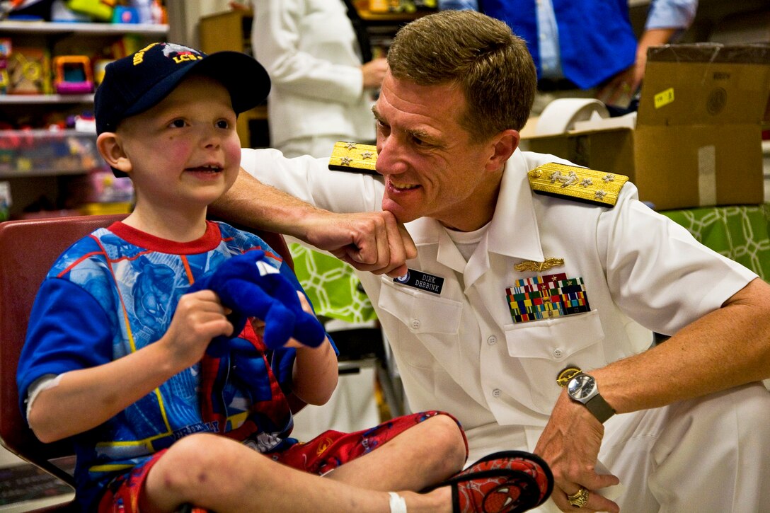 Navy Vice Adm. Dirk Debbink visits a patient during Caps For Kids, a Cincinnati Navy Week event at Cincinnati Children's Hospital, Aug. 29, 2011. Navy weeks showcase the investment Americans have made in their Navy and increase awareness in cities that do not have a significant Navy presence. Debbink is the Chief of Navy Reserve. 