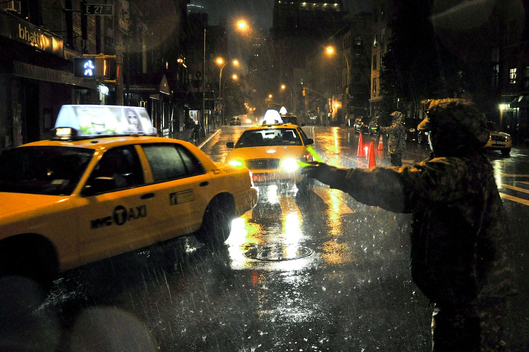 Army Pfc. Joel Hernandez and Cpl. Kevin Munoz, center background, direct cars away from Lexington Avenue Armory during Hurricane Irene to keep the area accessible for emergency and military traffic in New York, Aug. 27, 2011. Both are assigned to the National Guard. 