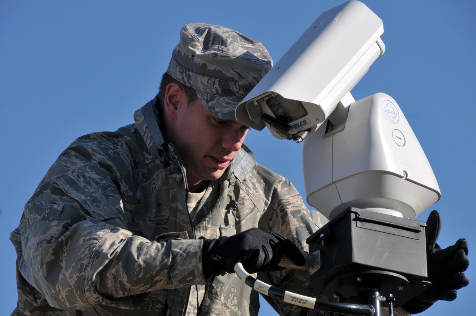 Air Force Tech. Sgt. Brent Trame, a client system technician with the Illinois National Guard's 126th Communications Flight, attaches cabling to a video camera, March 3, 2012. The camera is part of a Contingency Response Communications System.