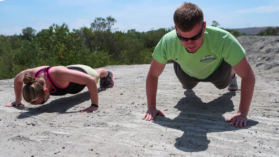 Corporal Dalton Pridmore, intelligence analyst, 15th Marine Expeditionary Unit, does pushups with his wife, Jamie Pridmore, in Oceanside, Calif., June 20, 2014. Pridmore and his wife are from Moody, Alabama. (U.S. Marine Corps photo by Lance Cpl. Anna Albrecht/Released)