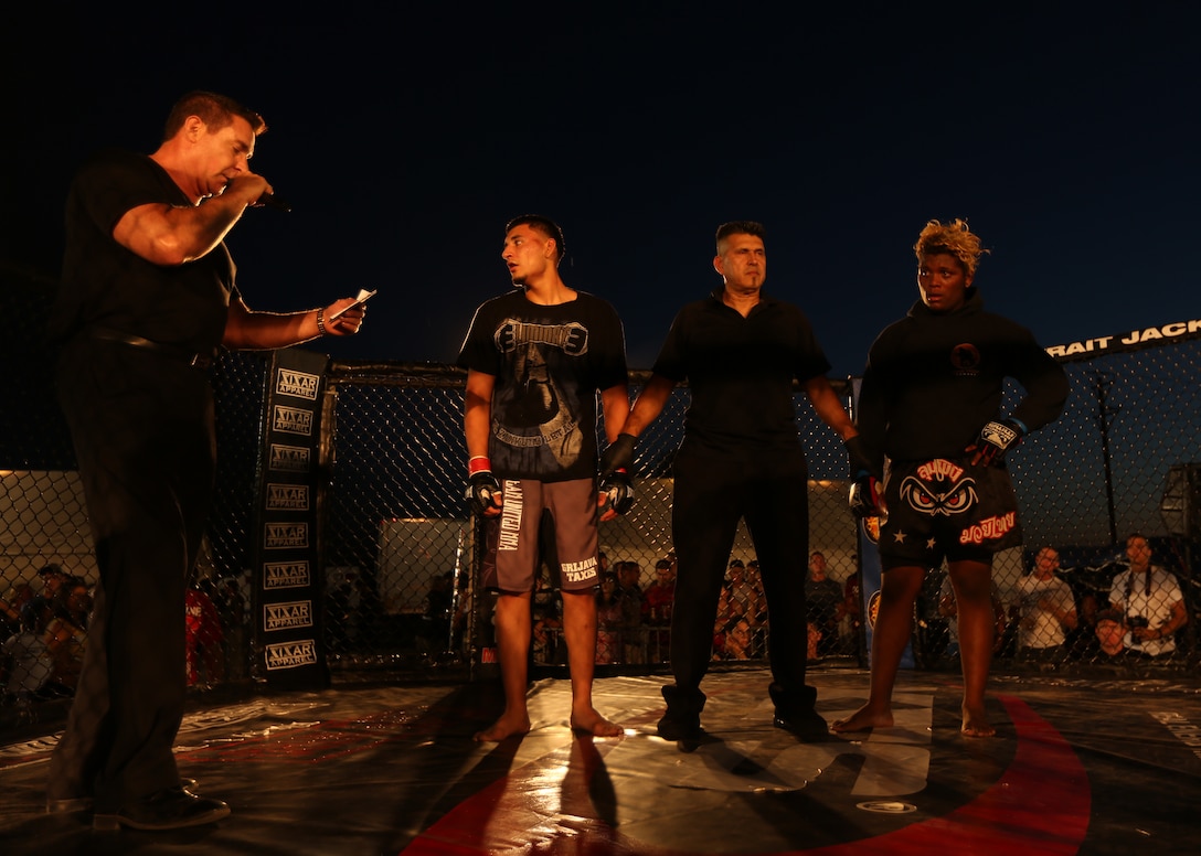 Carlos Kremer, announcer, prepares to declare the winner of a fight between Armando Mendez, fighter, Team United MMA, and Christian Padilla, fighter, Hardbody MMA, during Summer Fight Night V at Del Valle Field, June 20, 2014. Judges declared a winner if the fighters outlasted each other during three consecutive rounds.